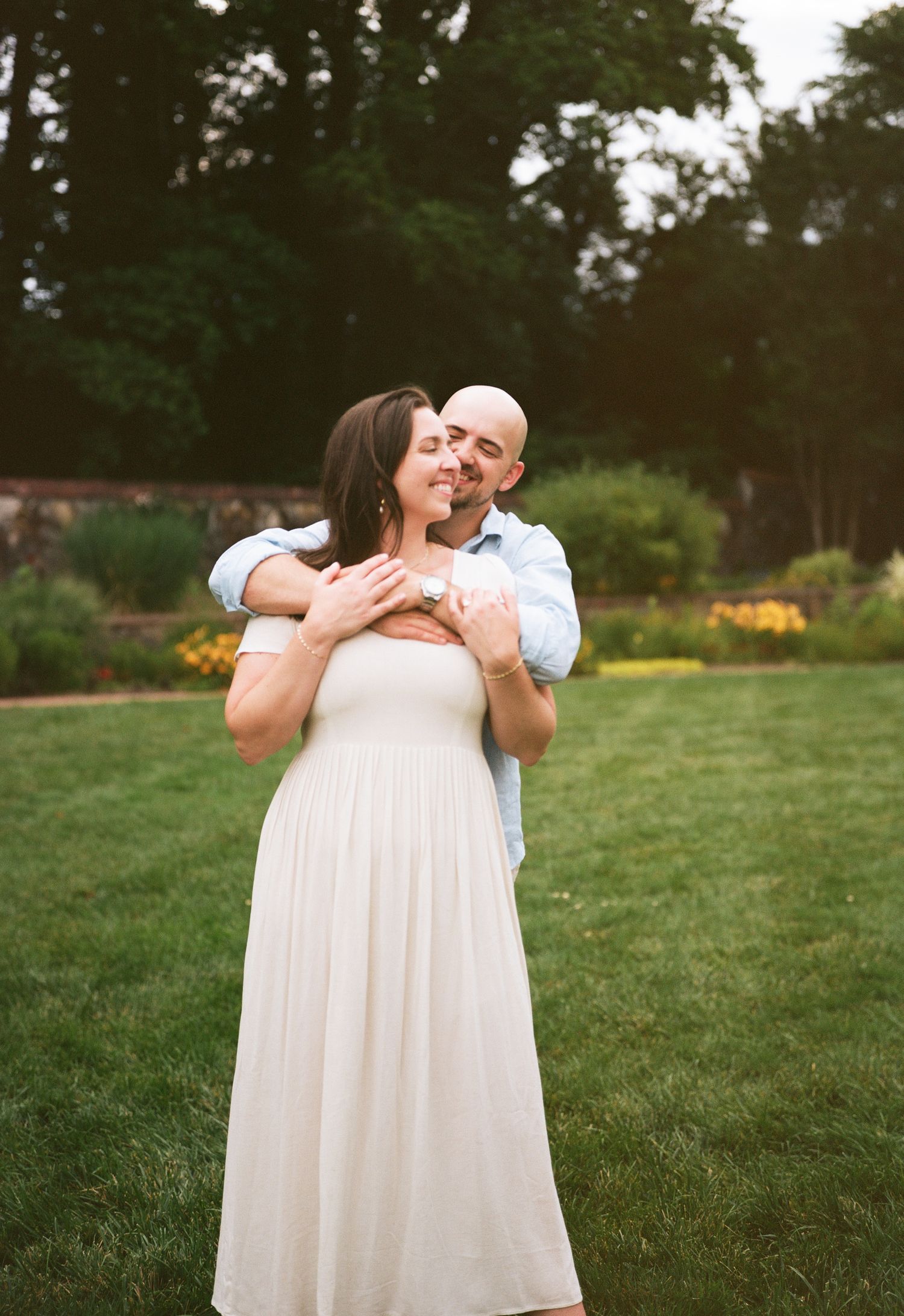 A tender embrace captured on a grassy lawn during golden hour.