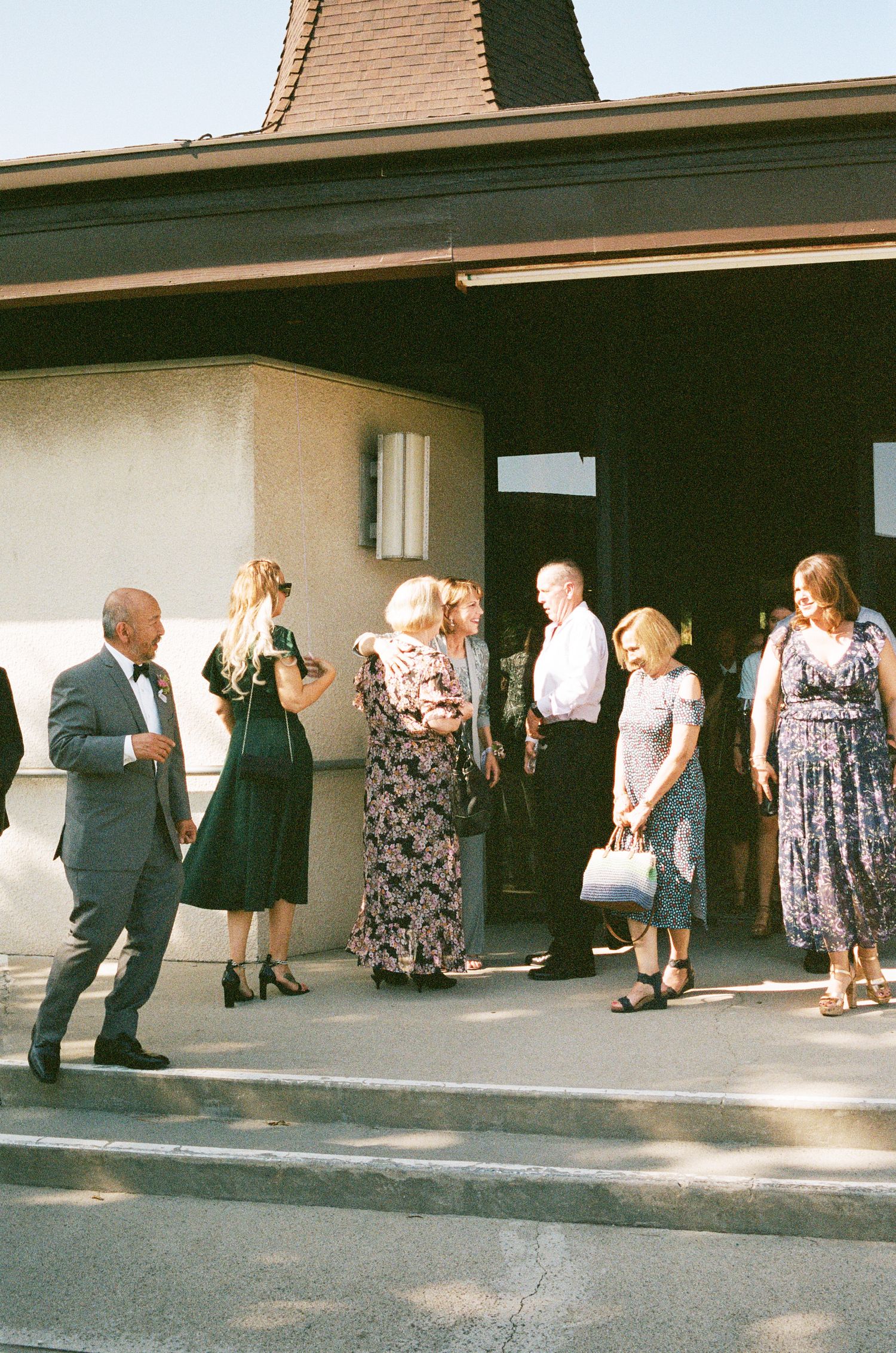 Wedding guests gathered outside a building entrance in formal attire.