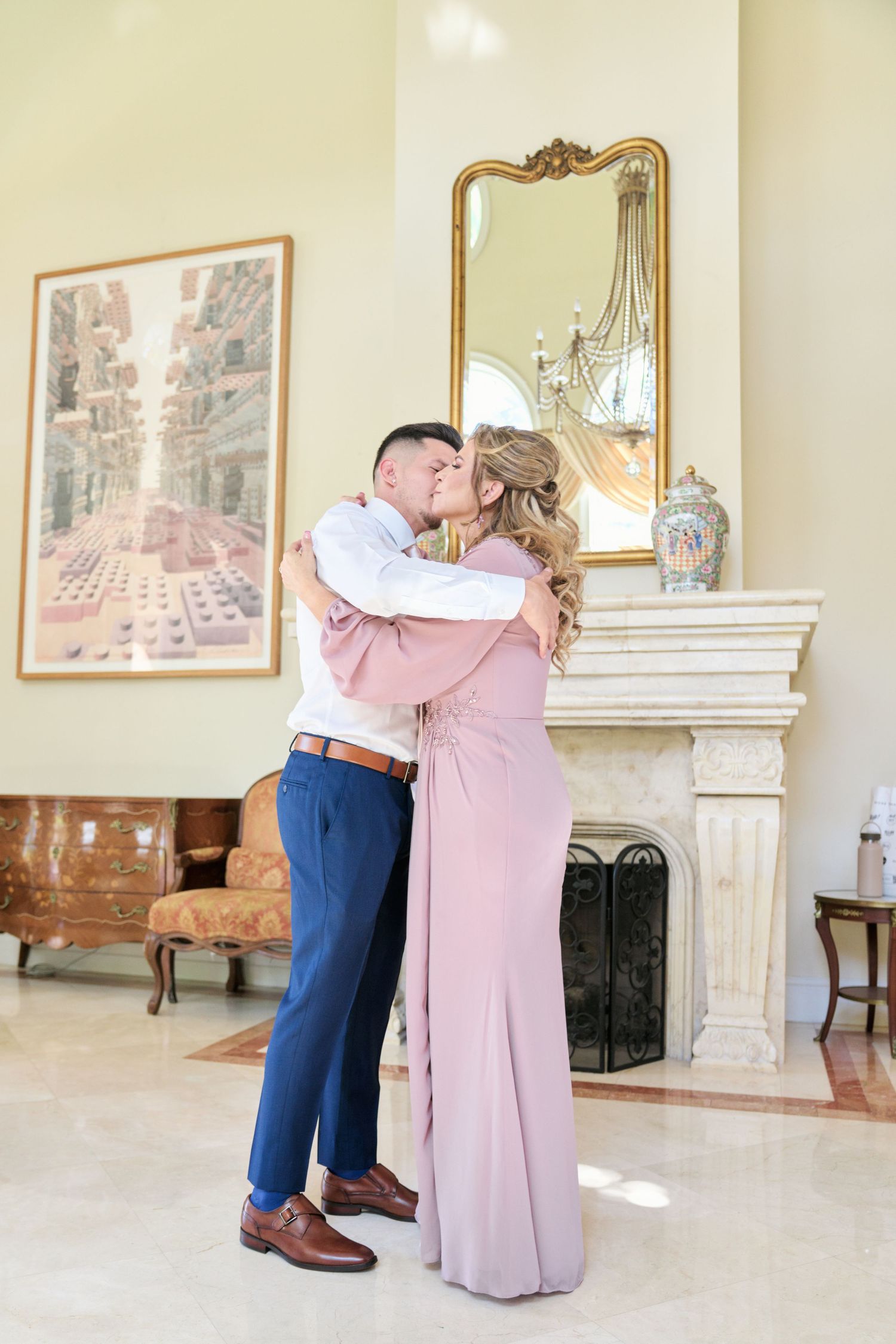 A romantic moment by an elegant fireplace with gold mirror and antique furniture.