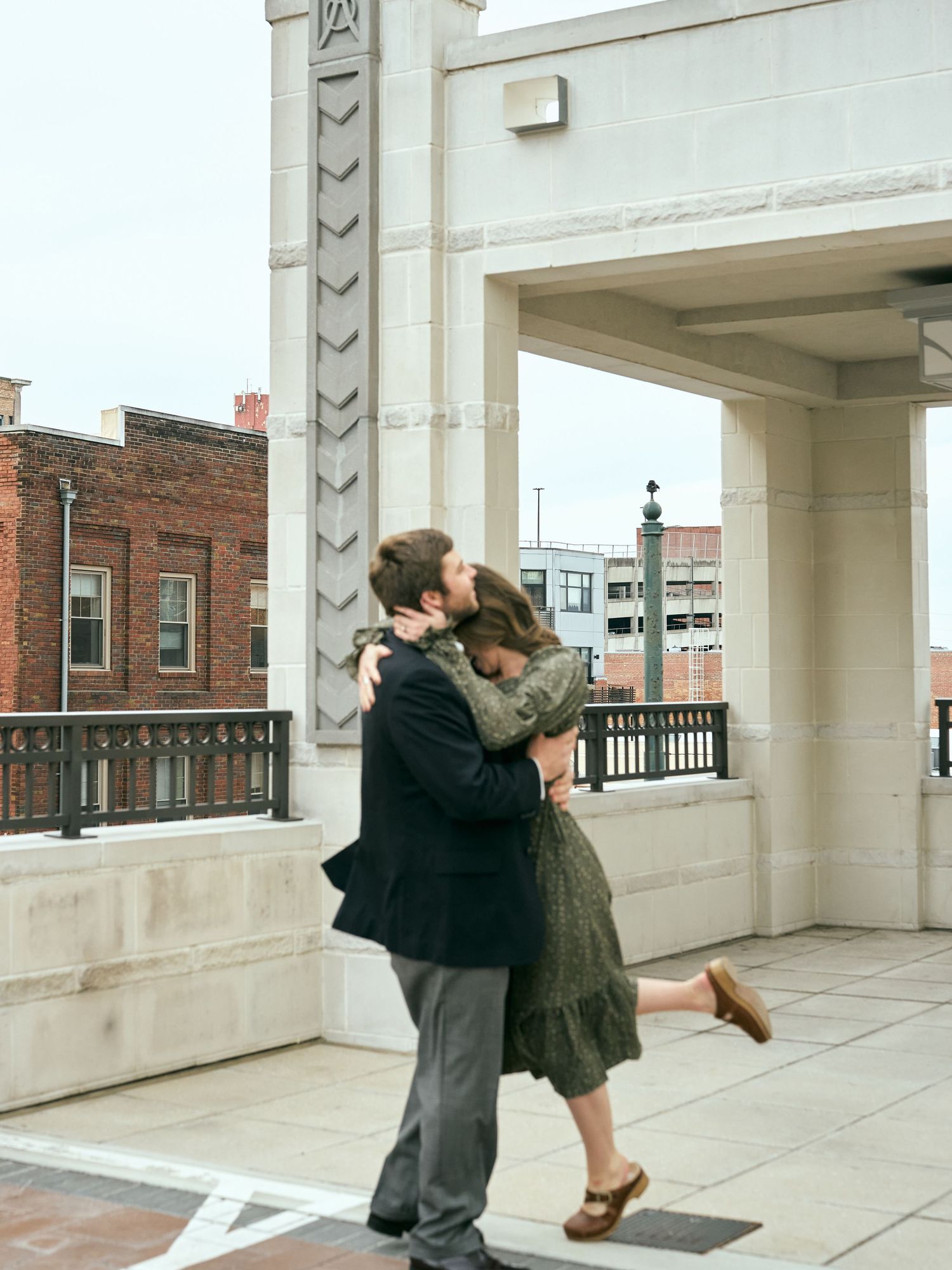 Two people share a romantic dance moment under a white architectural archway in an urban setting.