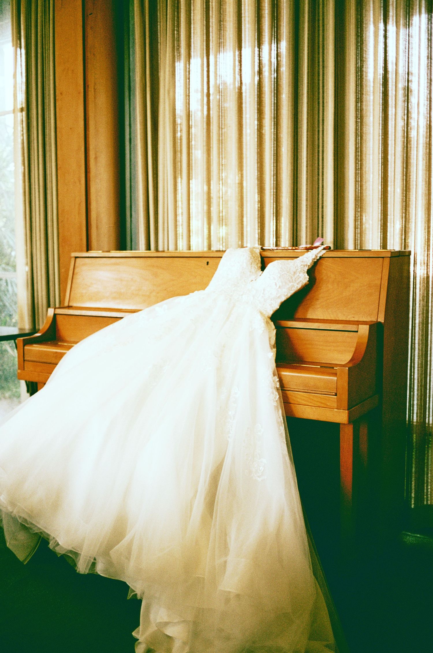 Elegant white wedding dress draped over a wooden church pew.