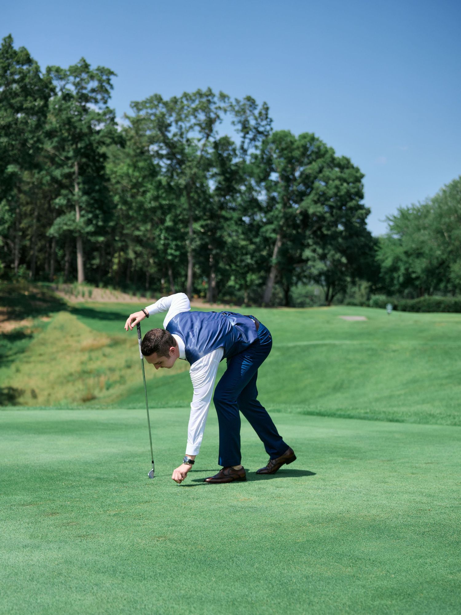 A golfer in blue attire placing a golf ball on a pristine green course.