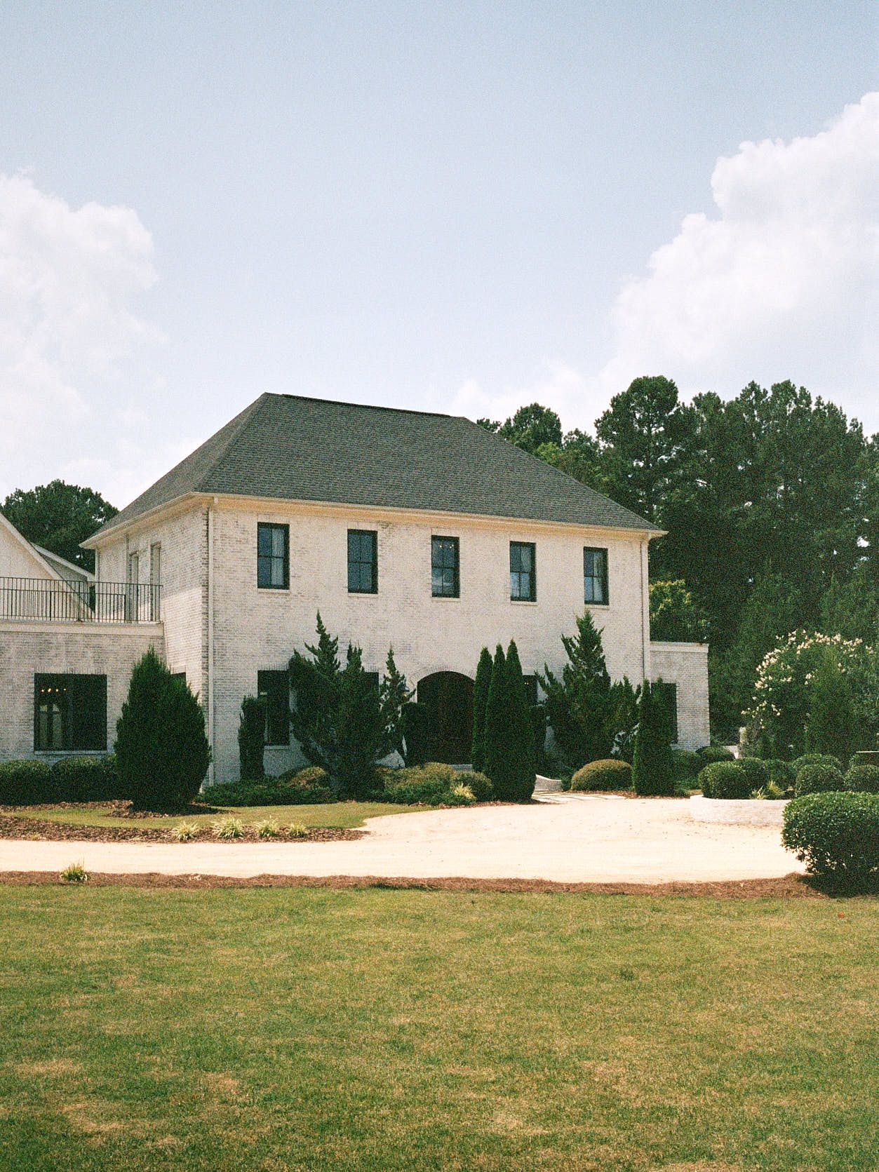 Two-story white stone venue with green roof and landscaped grounds.