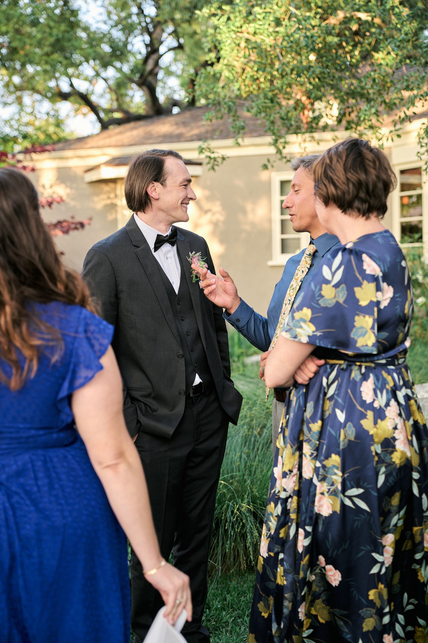 Outdoor garden party conversation among formally dressed guests in evening light.