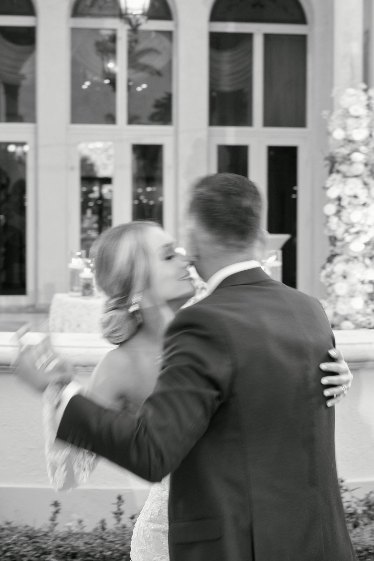 Black and white photo of an intimate moment during a wedding outside an ornate venue.