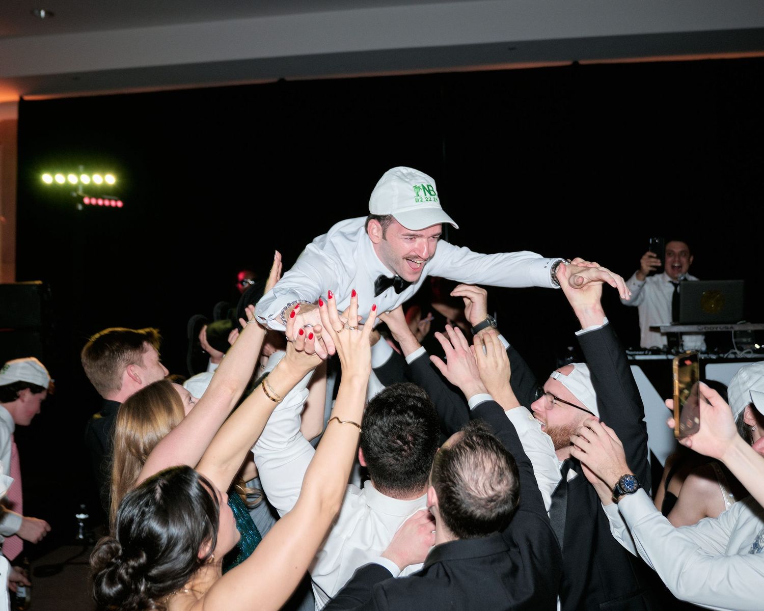 A crowd of concert-goers enthusiastically lifts someone above their heads during a high-energy performance.