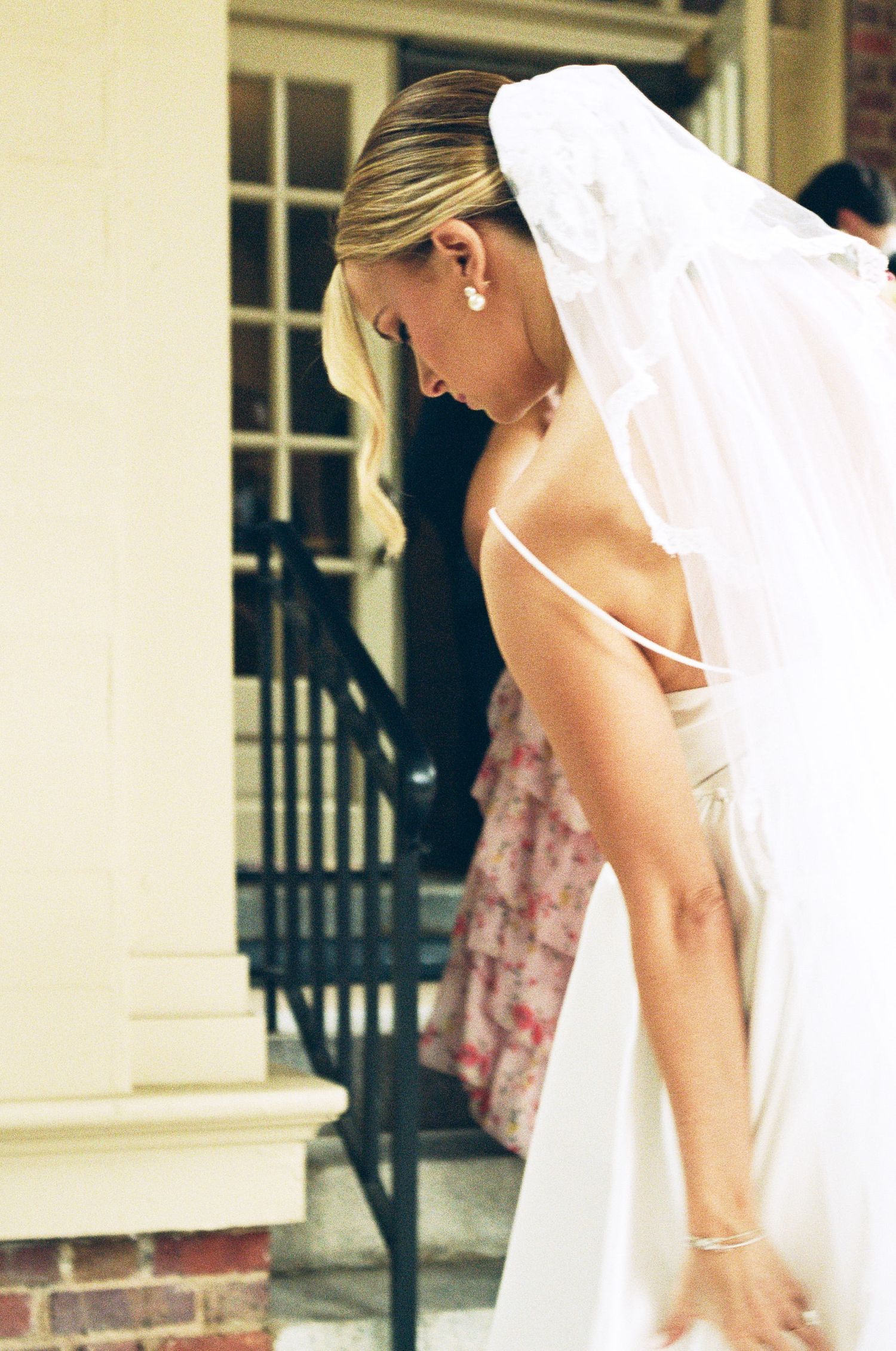 Close-up detail of bride's veil and profile against white column architecture.