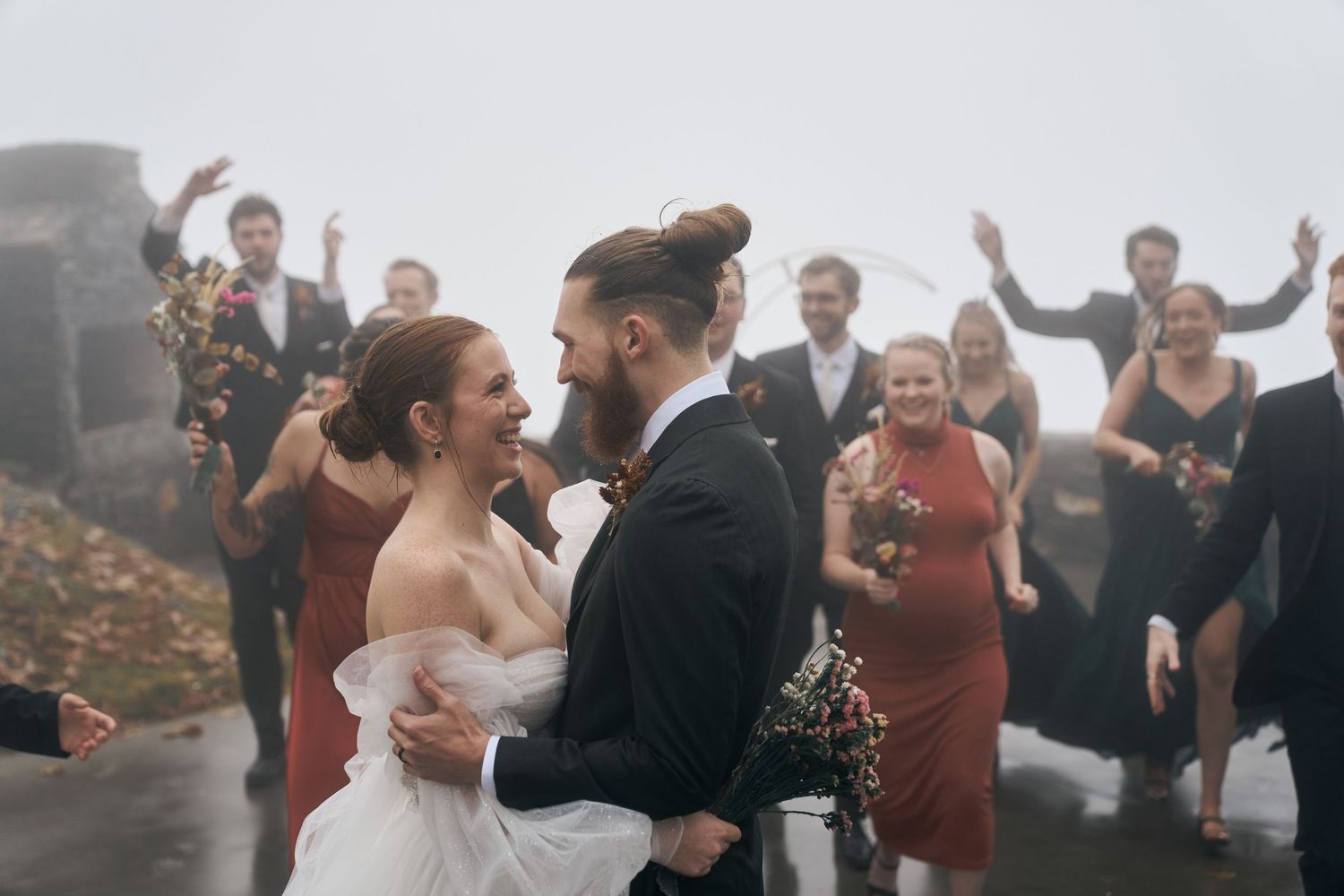 A joyous wedding celebration with guests cheering on a misty mountaintop.