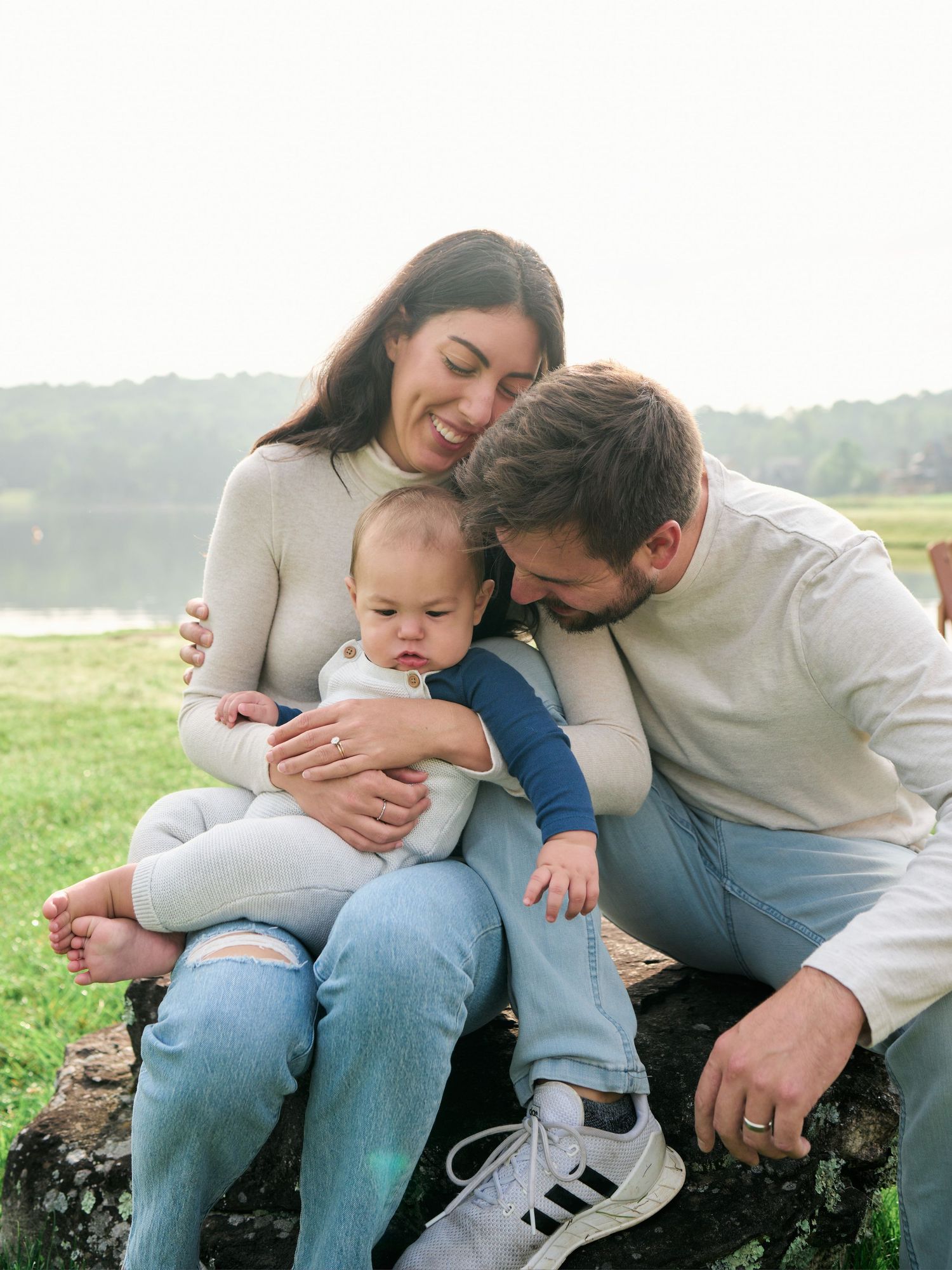 A family sits together on a stone wall outdoors, sharing tender moments and embraces in a series of candid photos.