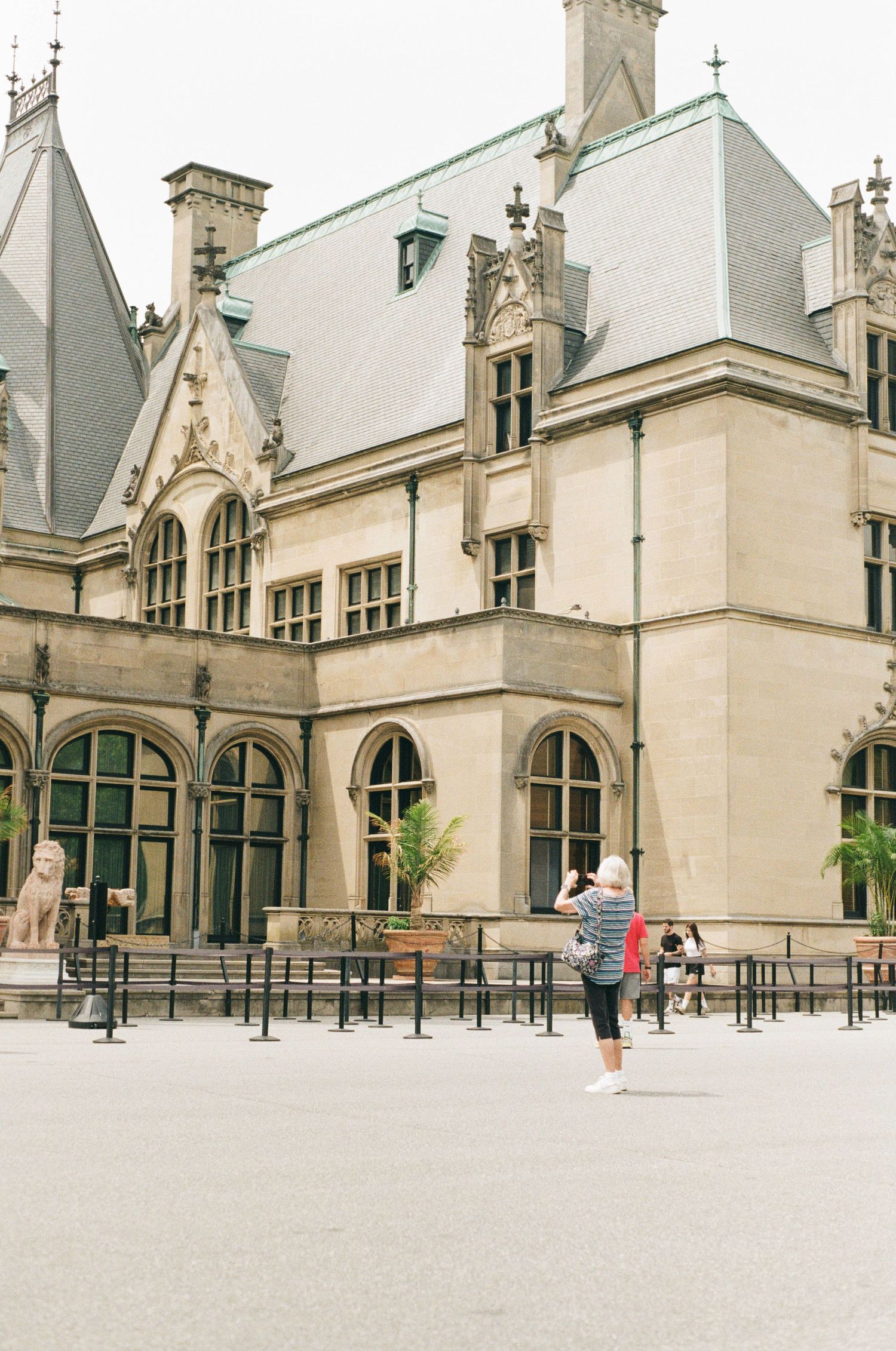 Photo of a tourist taking a photo in front of the Biltmore Estate House.
