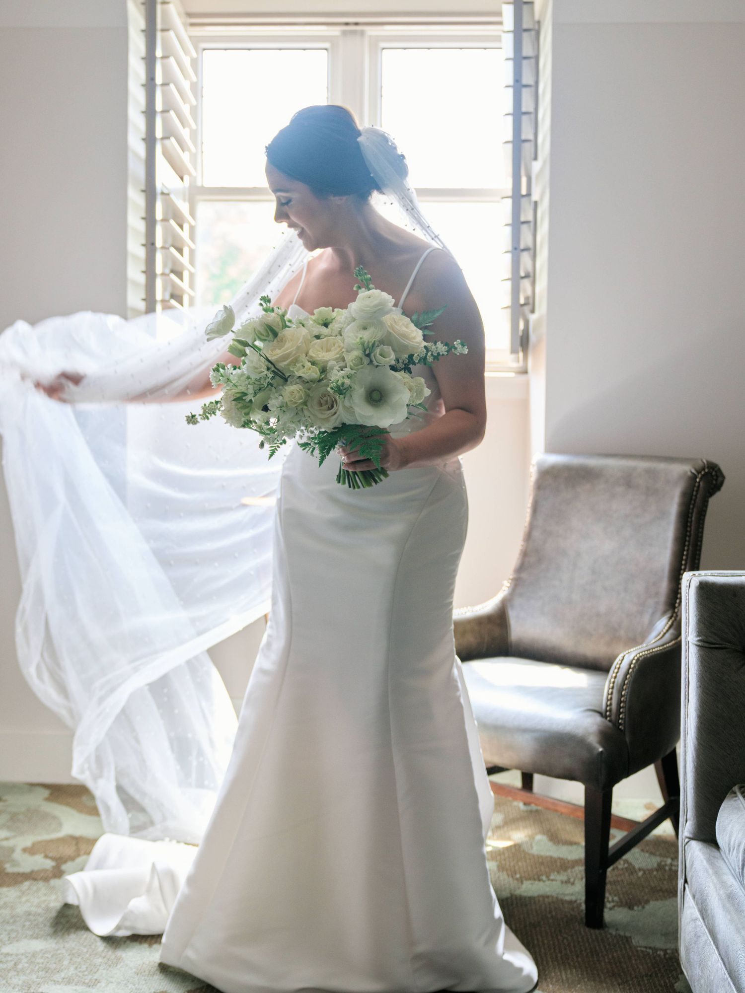 Bridal portrait fixing her dress standing in front of a window at the grand bohemian hotel.