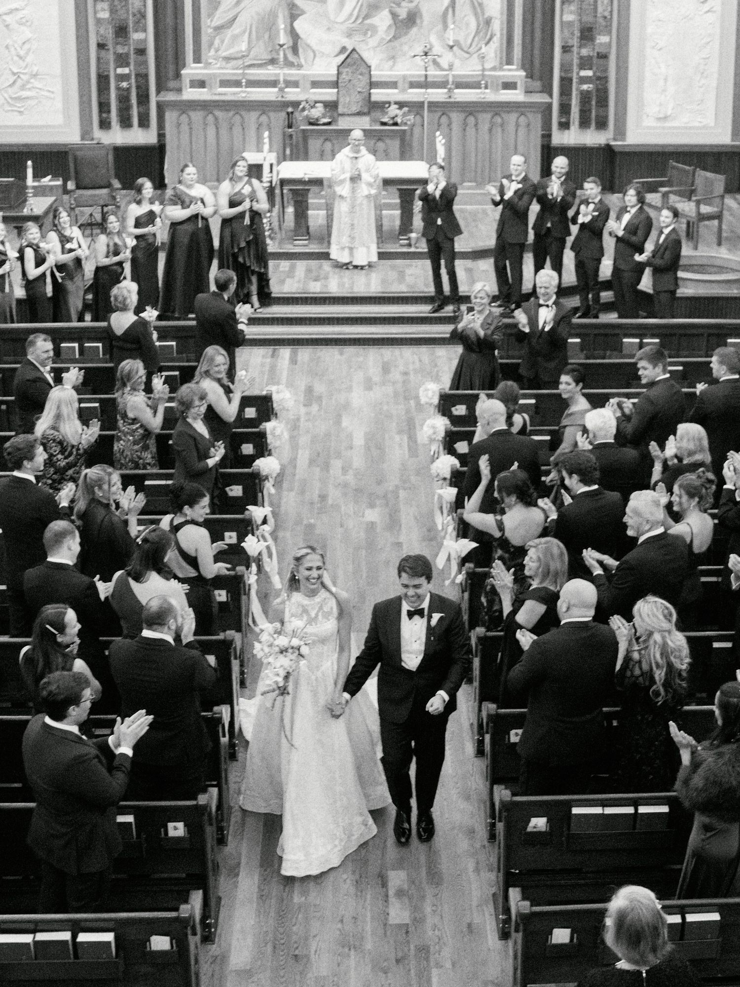 Black and white photo of a bride and groom walking down the aisle after their church wedding ceremony.