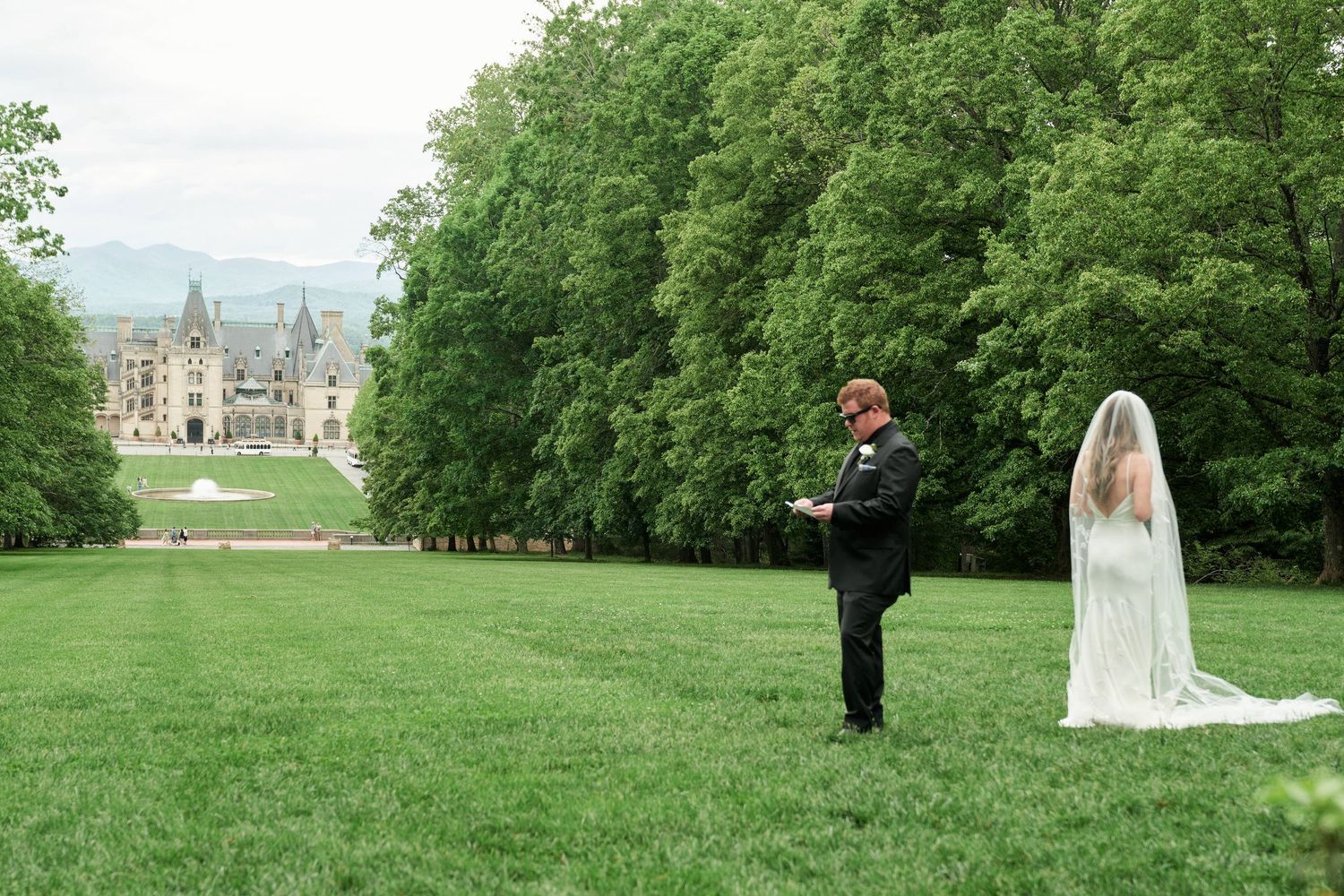 Couple celebrates their wedding day in a lush green garden setting with a historic castle in the background.