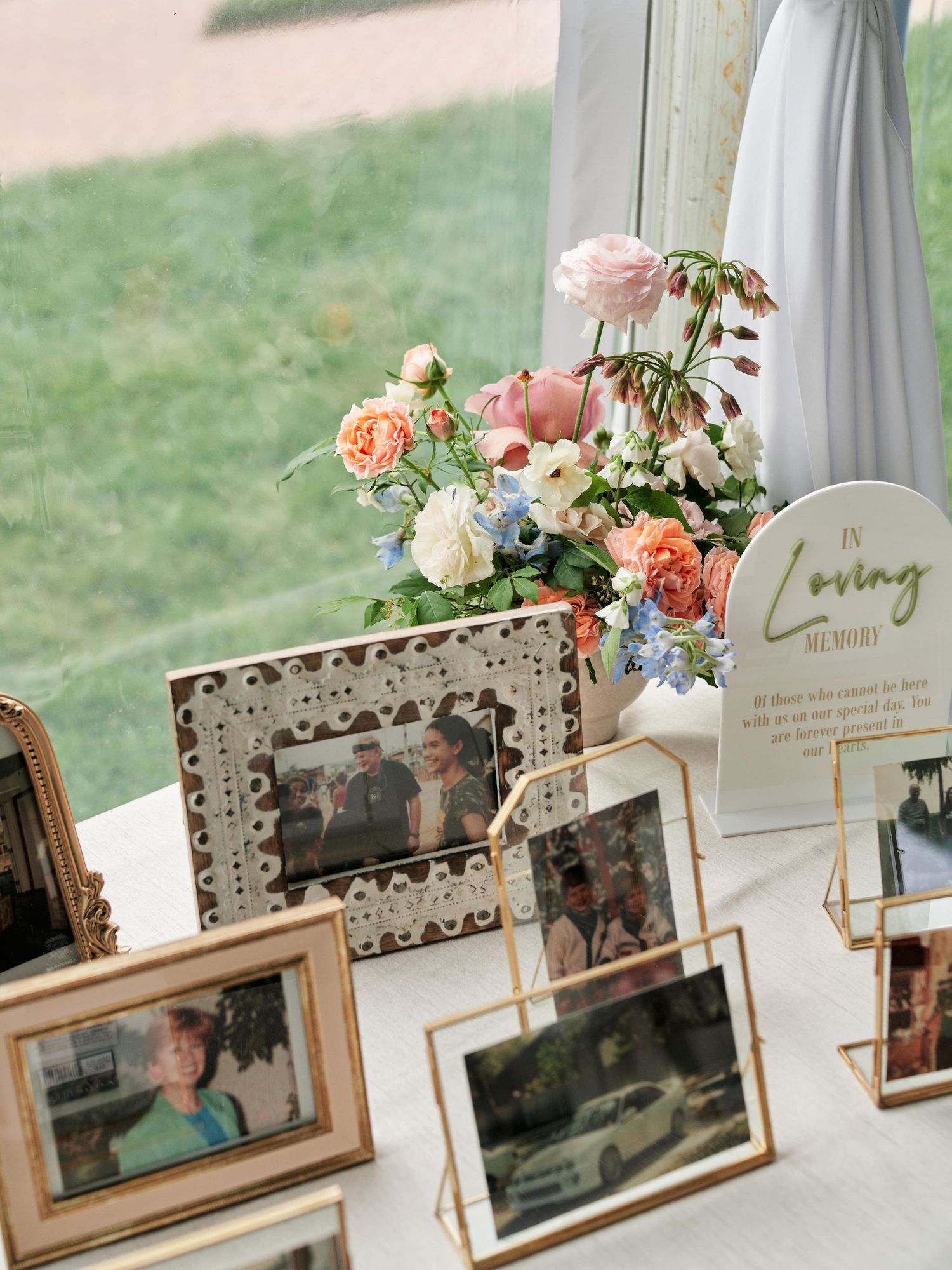 Rustic wedding photo display with floral arrangements featuring peach and white roses on wooden stands.