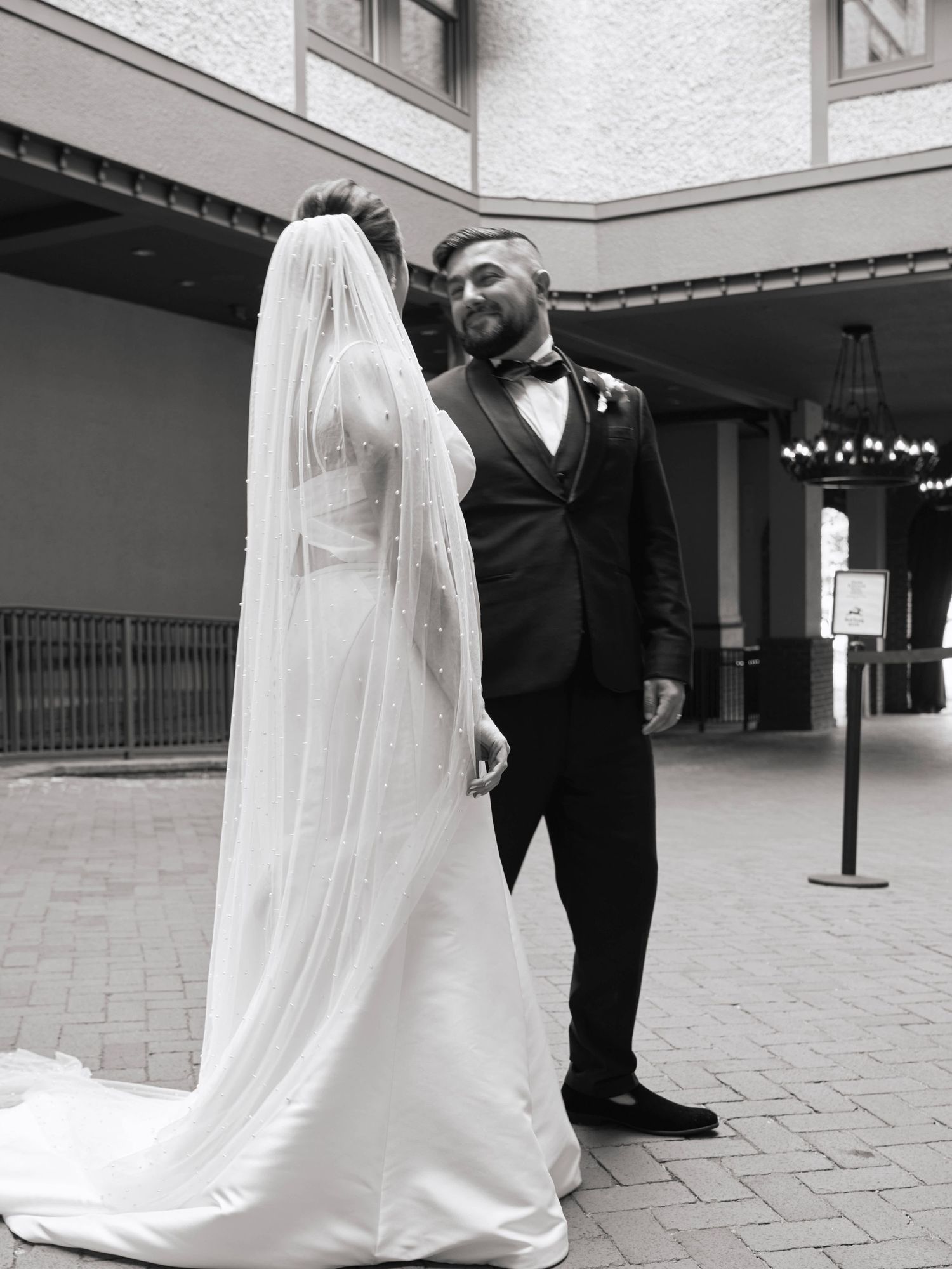 Black and white wedding photos show a couple in formal attire dancing together in a courtyard setting.