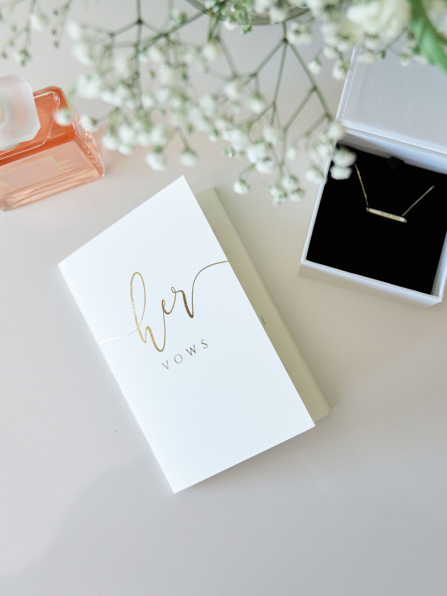 Wedding jewelry box with gold text and delicate baby's breath flowers on light background.