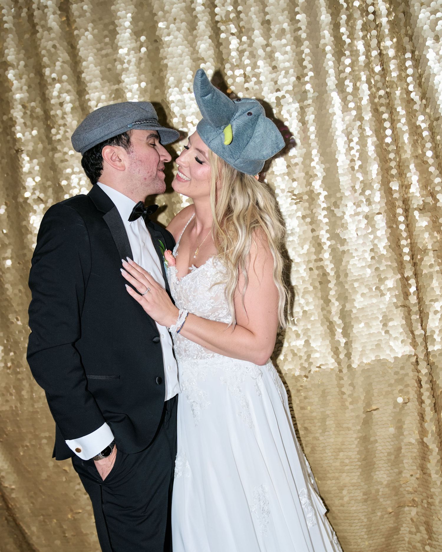 Newlyweds pose against a gold sequin backdrop with fun props during their wedding reception.