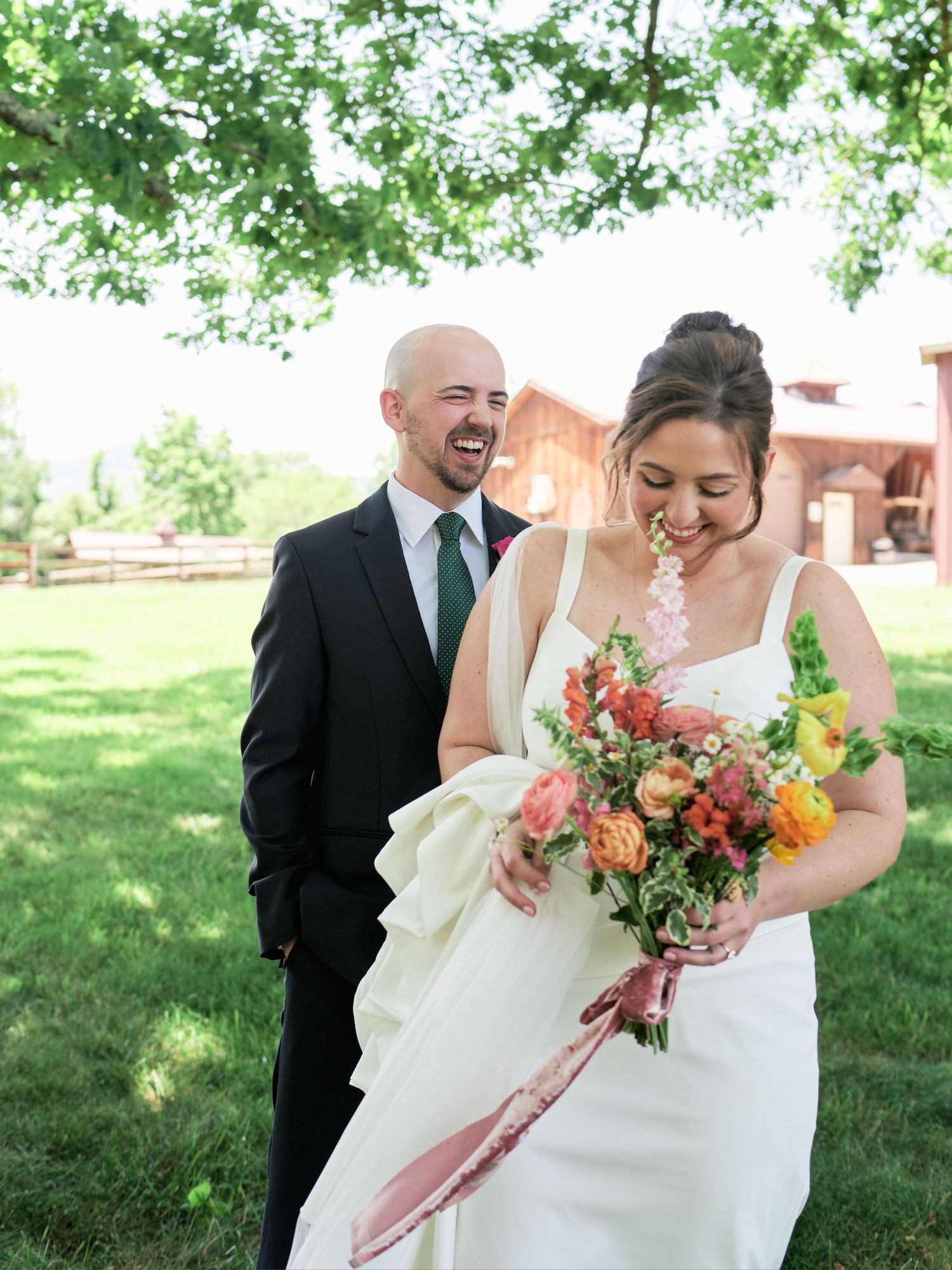 Joyful wedding moment with bride holding colorful bouquet while groom laughs behind her.