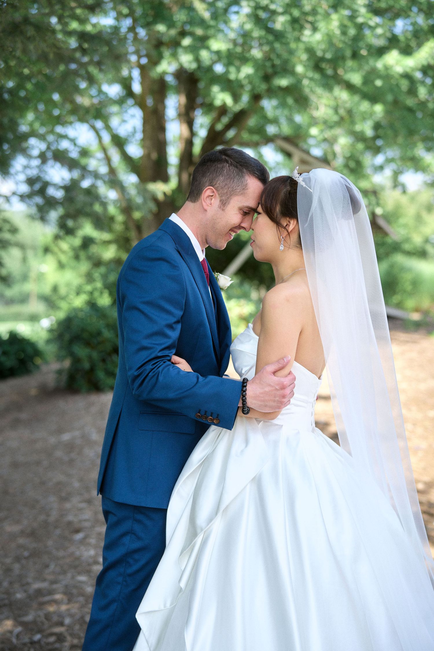 A romantic moment between newlyweds embracing on a wooded path.