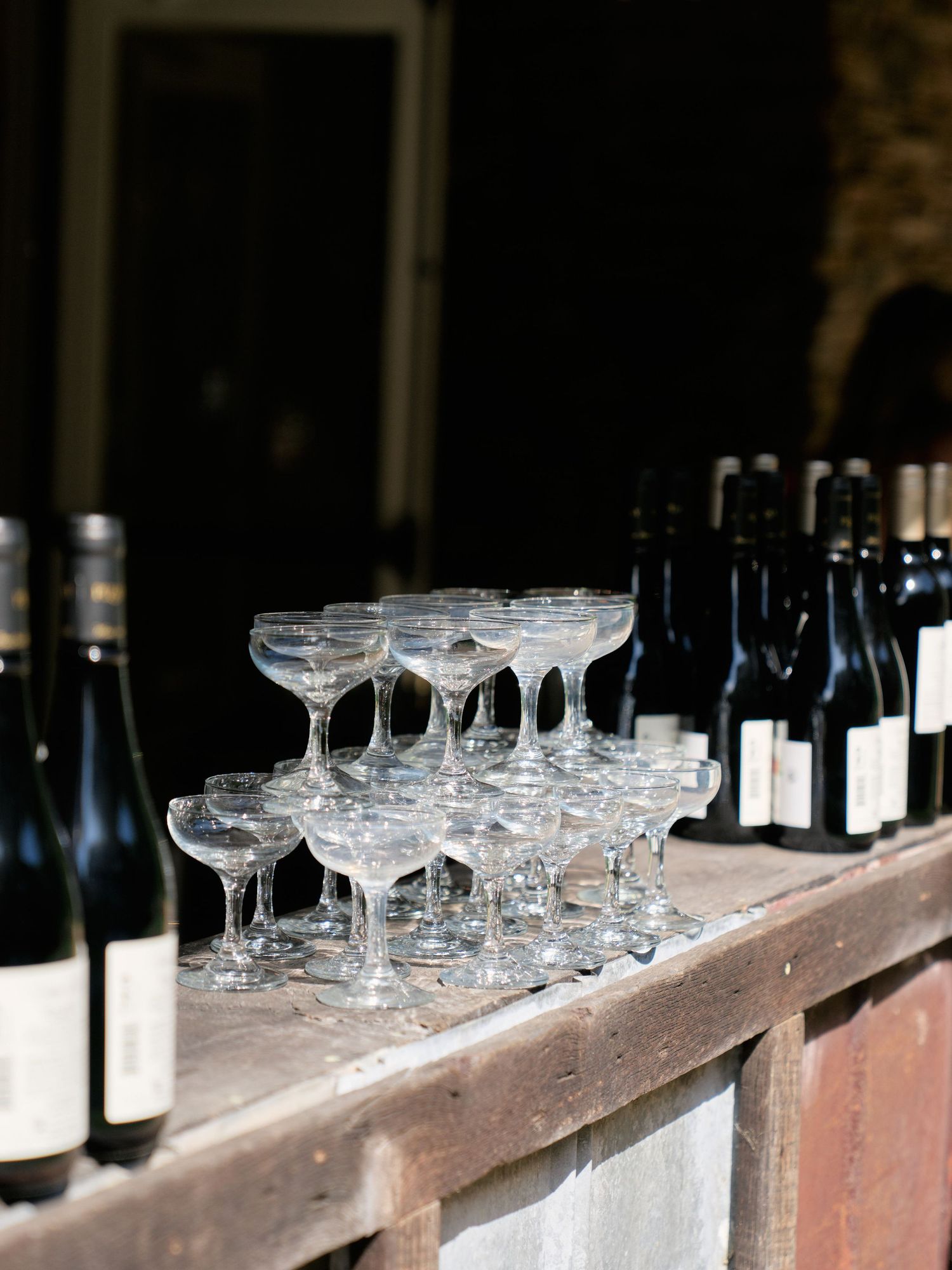 Champagne glasses and wine bottles arranged on a rustic wooden bar counter.