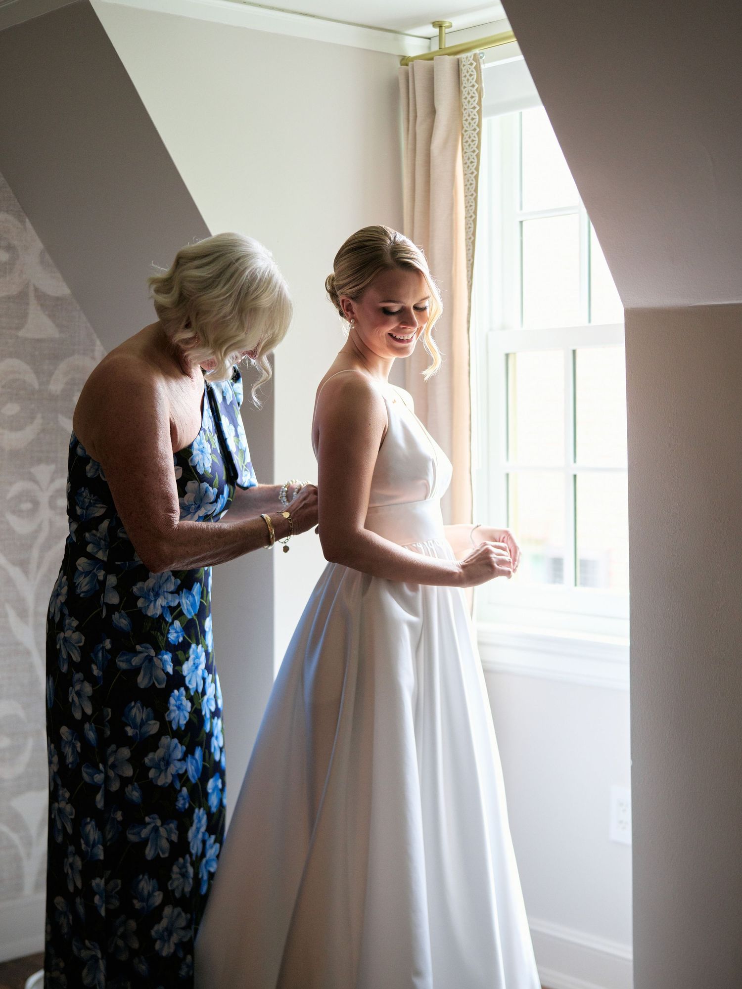 Final wedding dress adjustments being made near window in natural light.