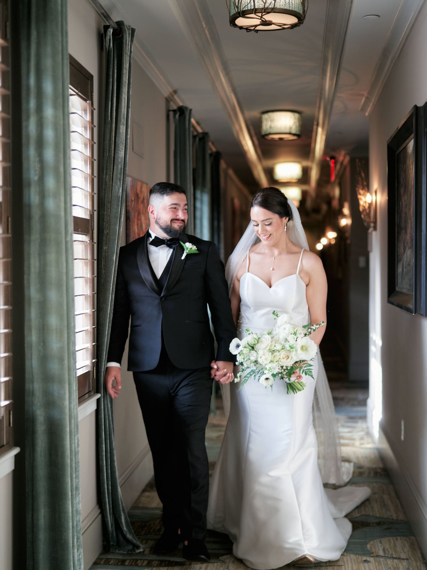 Elegant couple walking hand in hand down a hallway during their wedding.