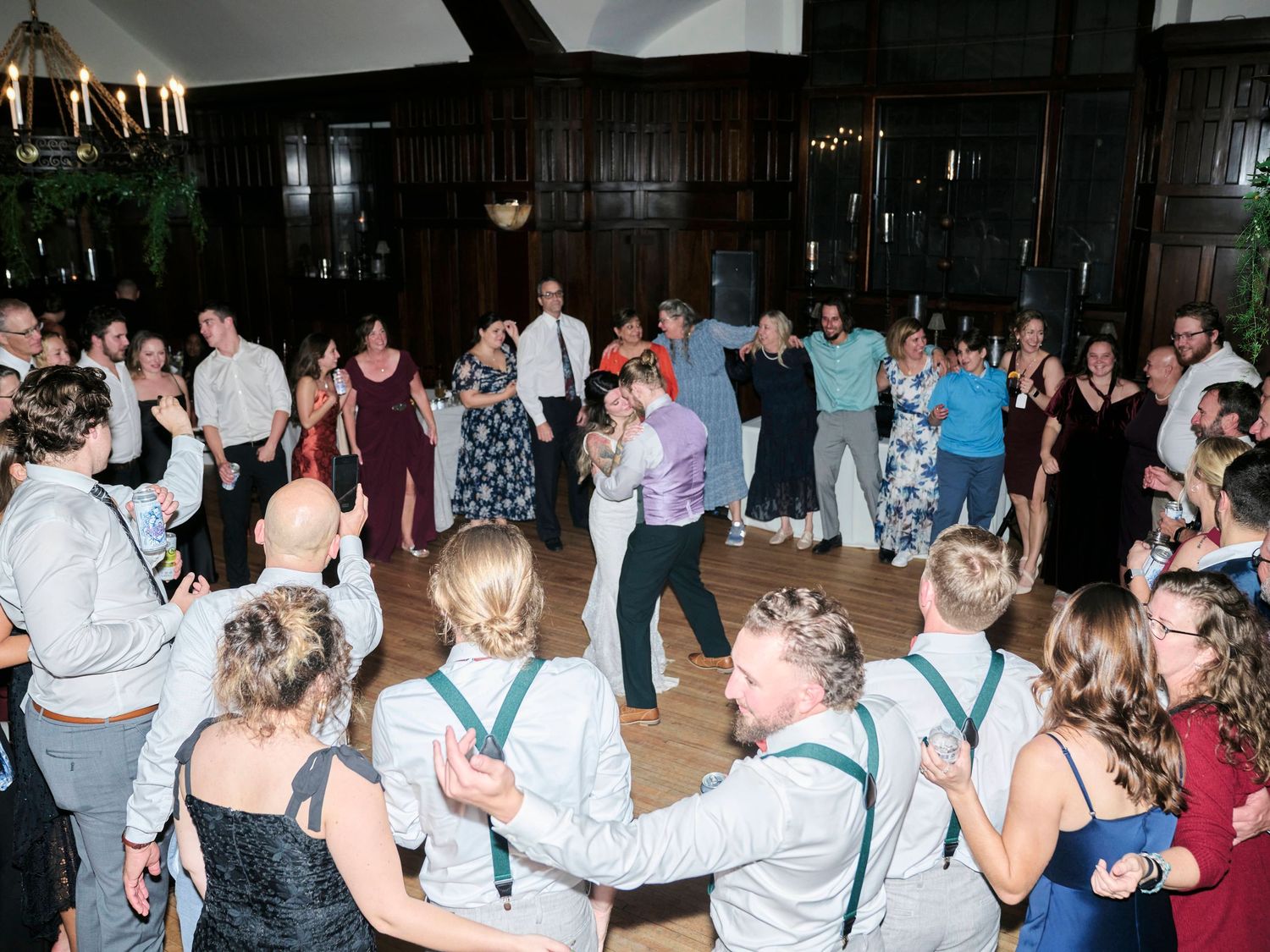 Large group of wedding guests dancing and celebrating in an elegant ballroom.