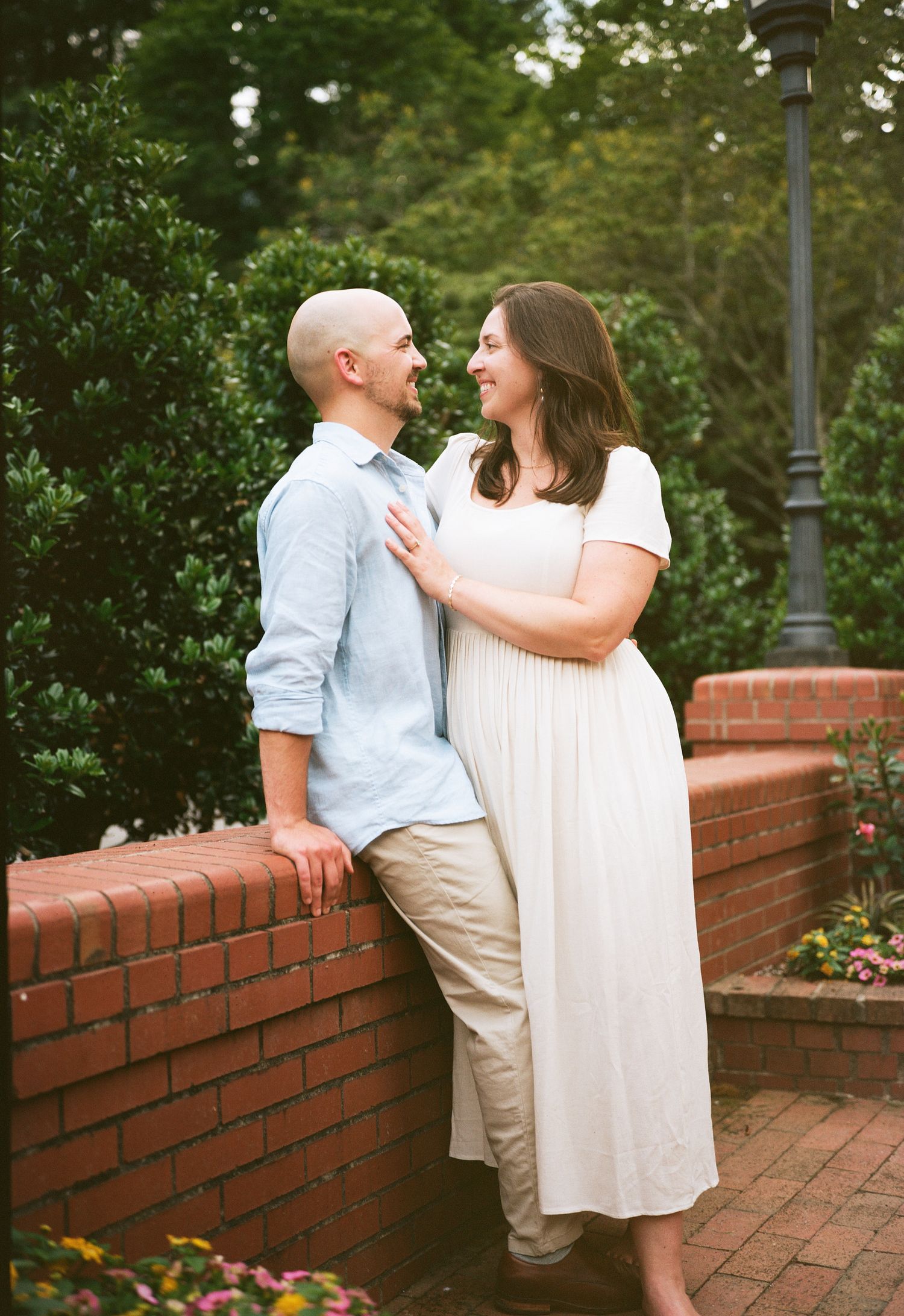 A romantic moment shared against a backdrop of lush greenery and brick walls.