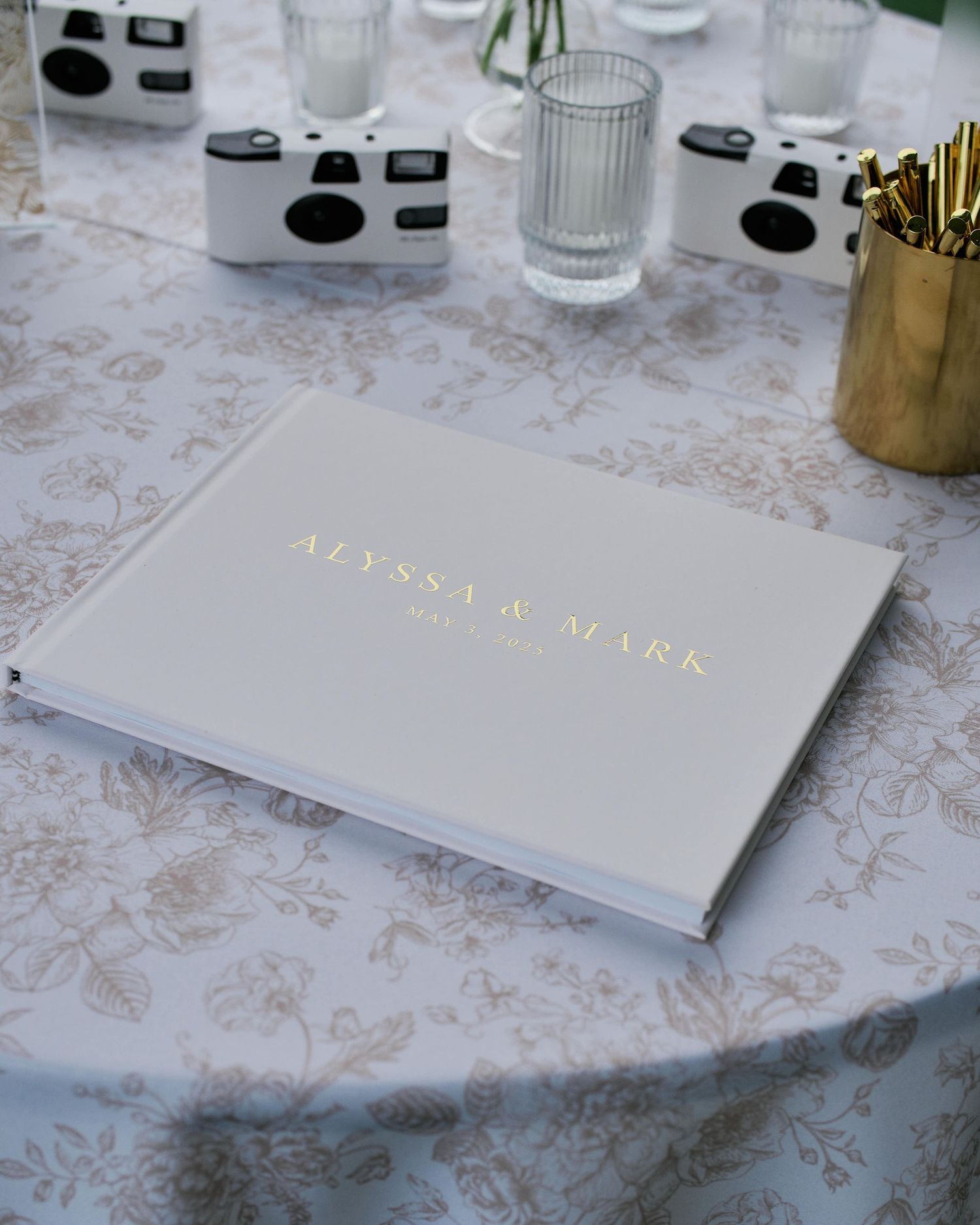 A white and gold branded notebook or planner sits on a marble textured surface.