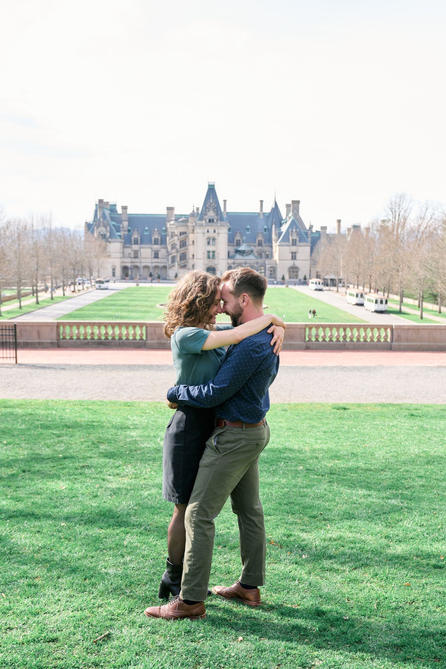 romantic photos of couples touching foreheads in from of the Biltmore House during their engagement photos.