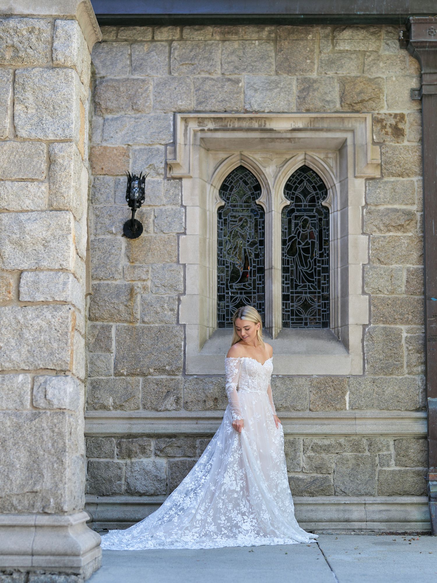 Elegant wedding dress with lace detailing photographed against gothic church architecture.