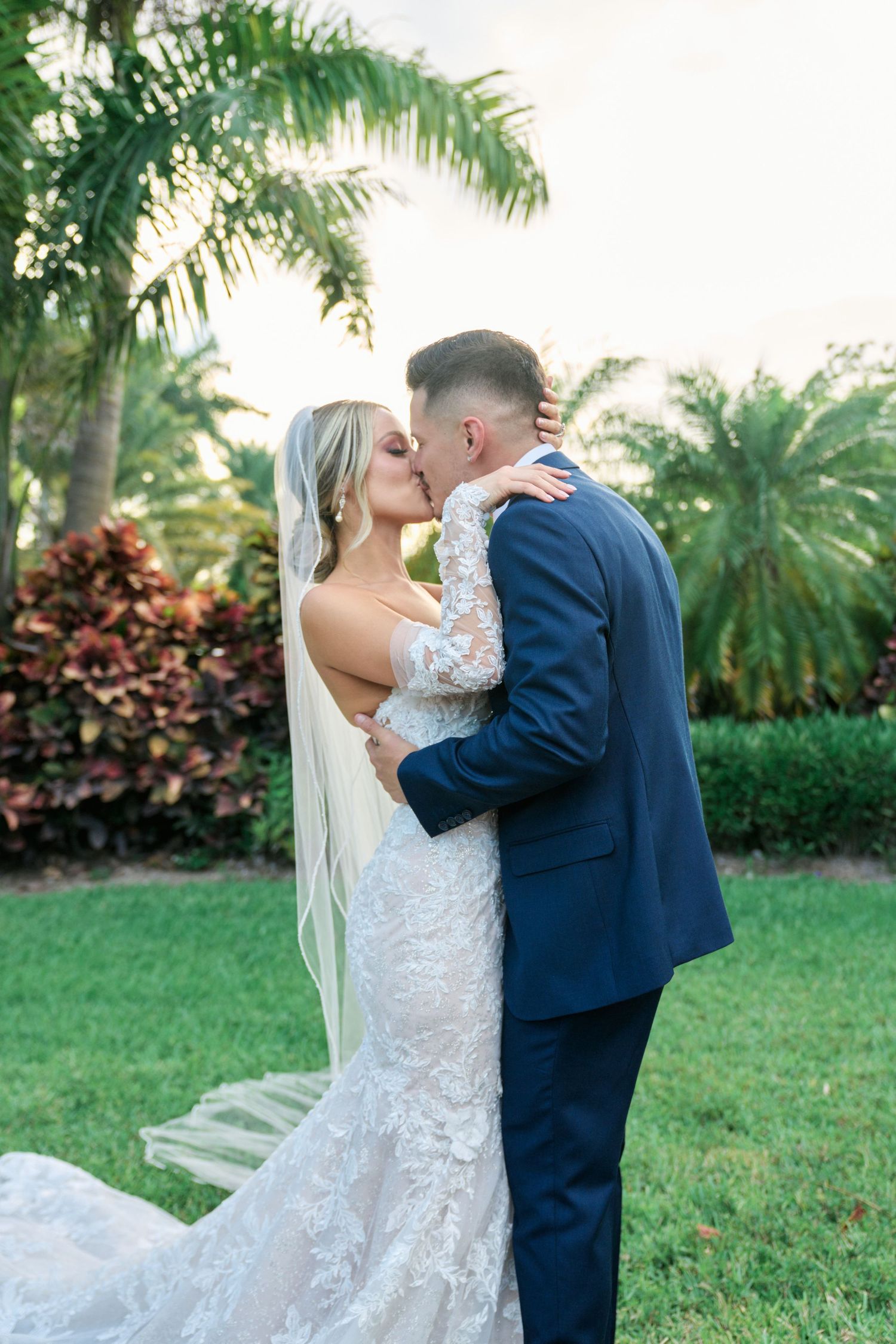 Tropical garden wedding portrait with palm trees and flowing veil.