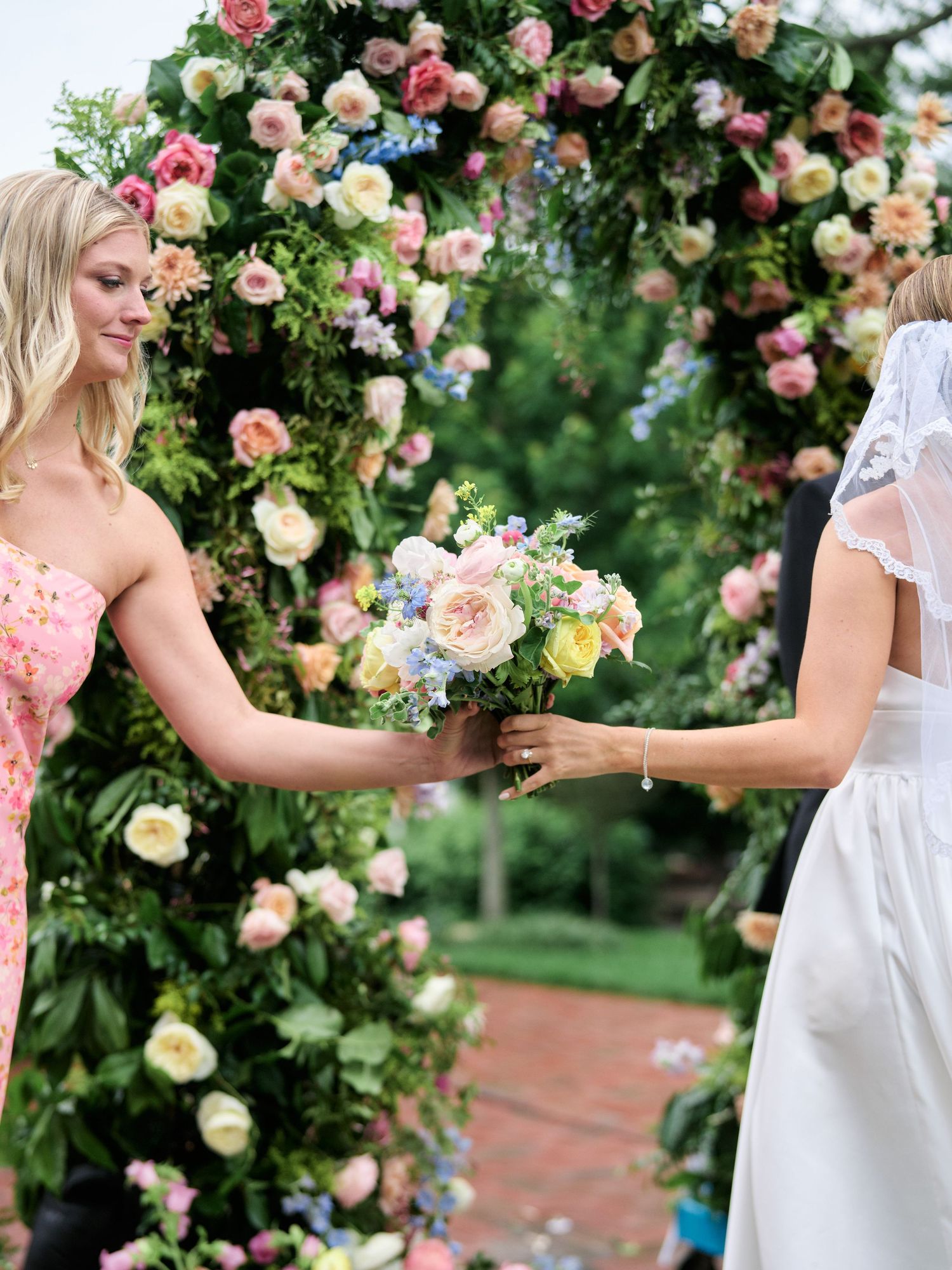 Beautiful floral arch with pink and peach roses frames wedding ceremony moment.