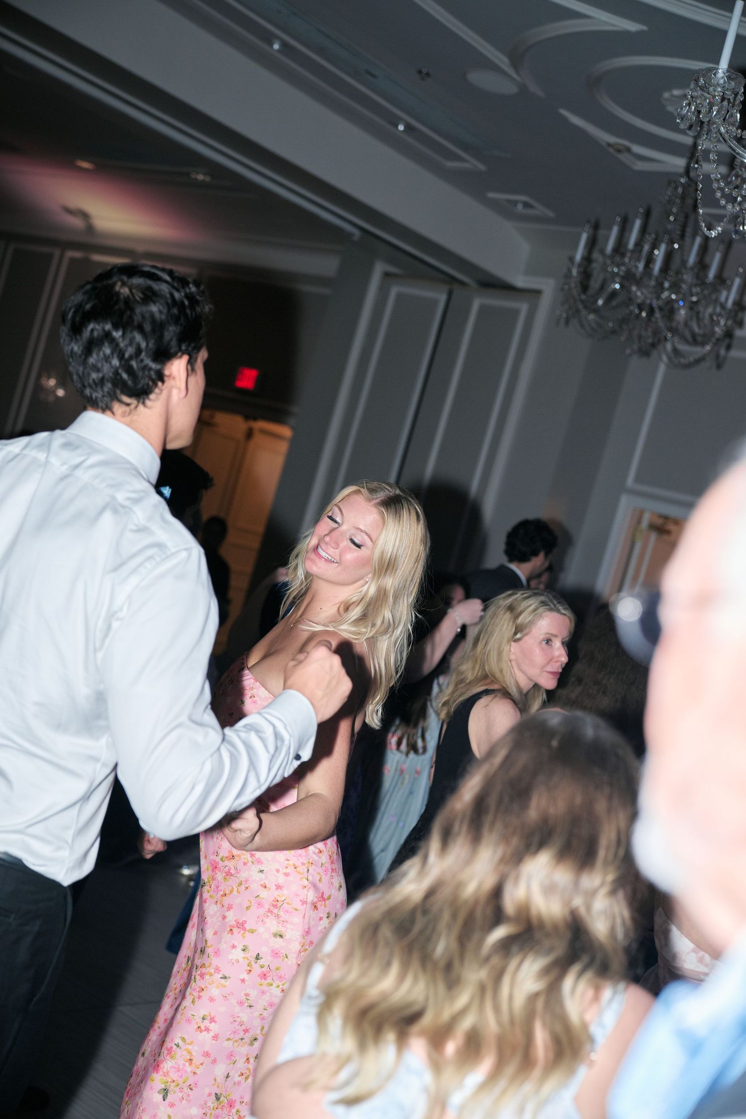 Wedding guests enjoying themselves and laughing while dancing at an elegant reception venue.