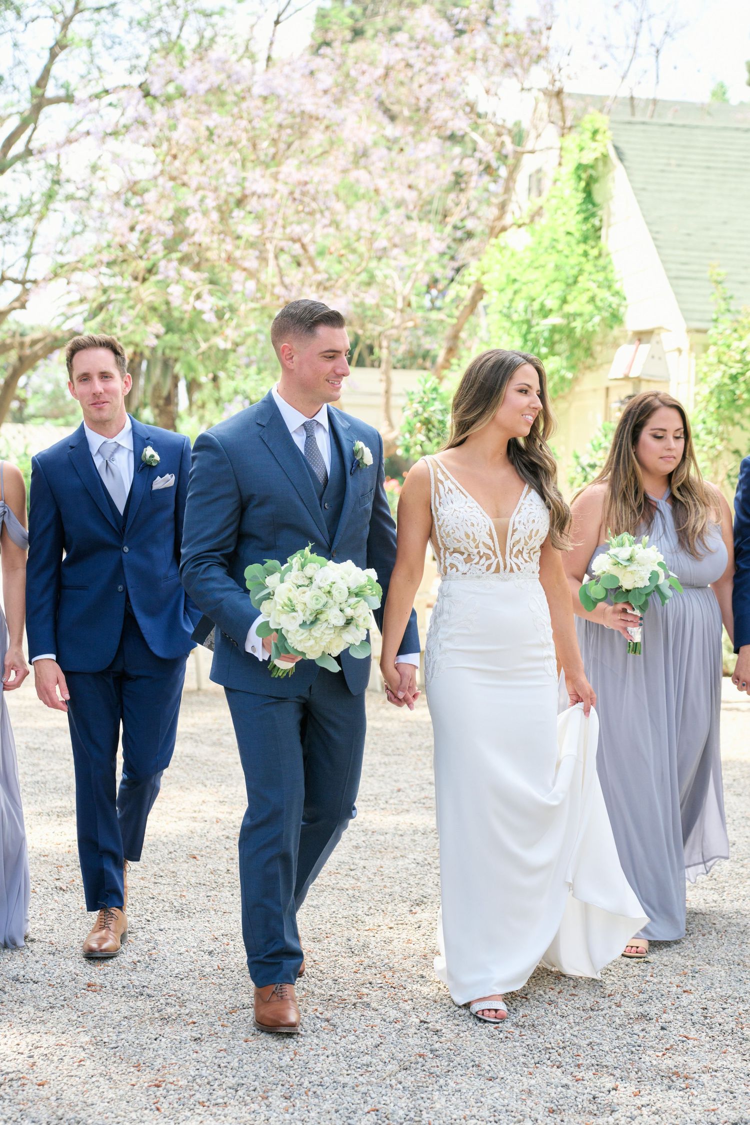 Wedding party walking together with bridesmaids in lavender and groomsmen in navy suits.