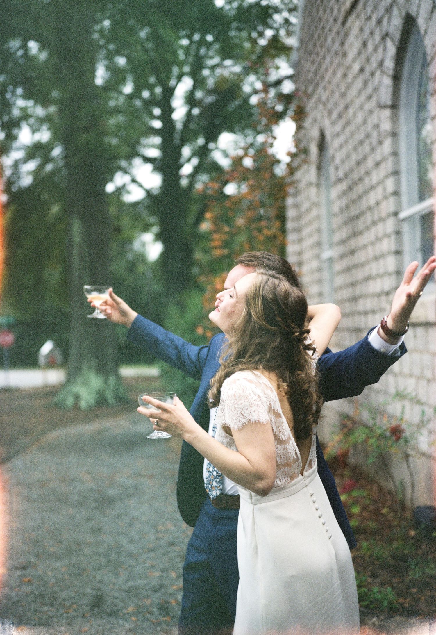 Celebratory moment outside a historic brick building with guests holding champagne glasses.