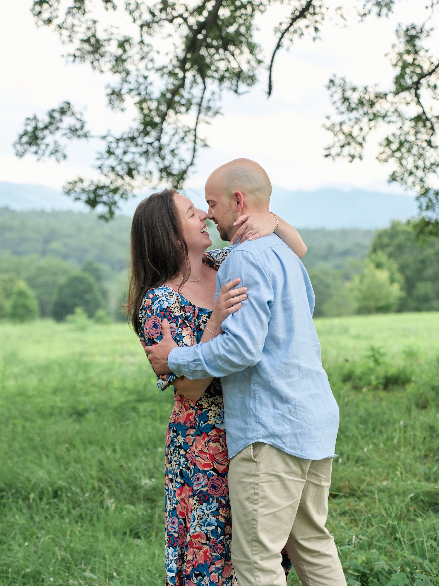Intimate portrait of couple sharing tender moment in scenic mountain meadow.