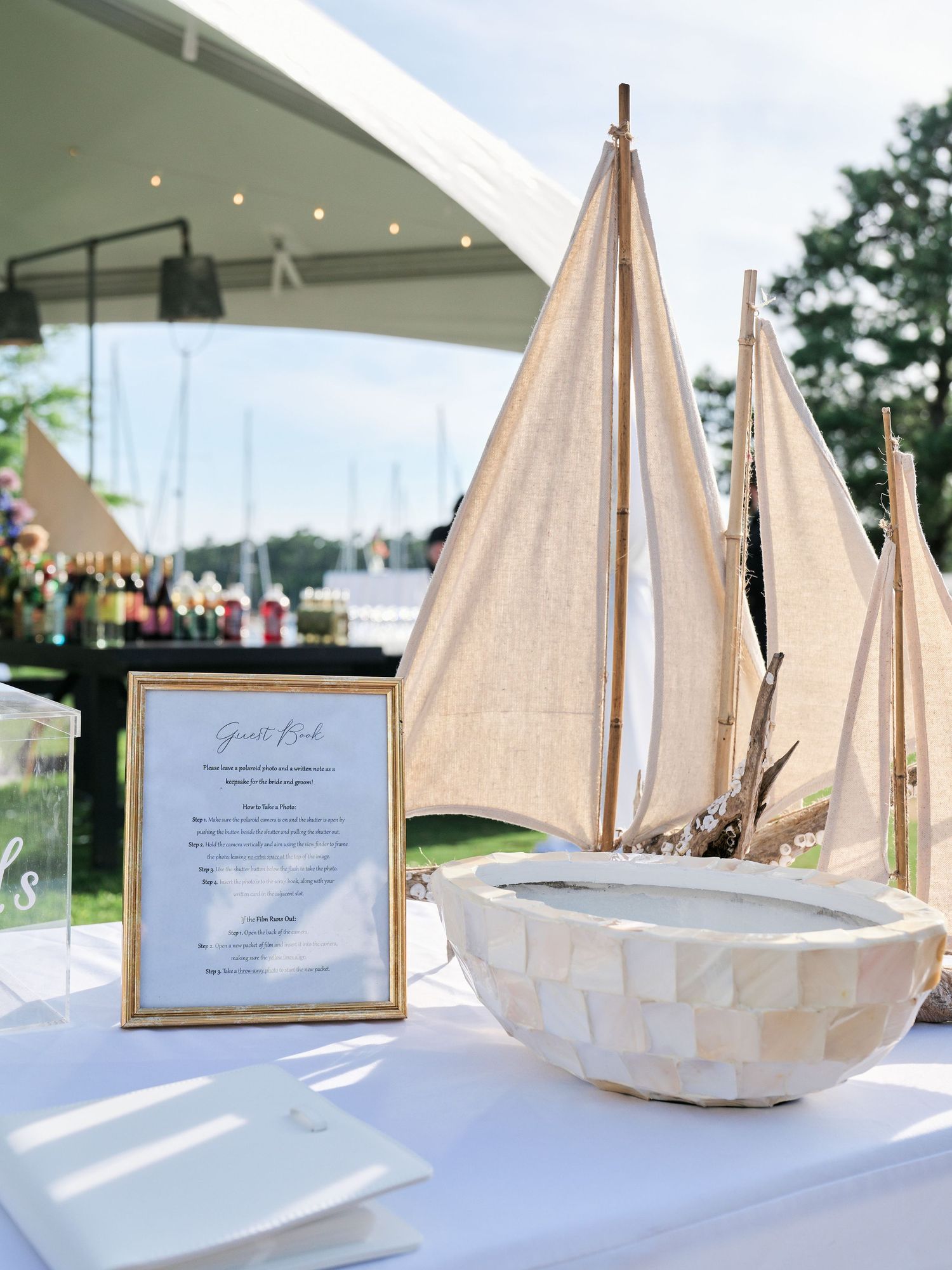 Elegant nautical-themed buffet table with decorative sailboats and framed menu card at an outdoor event.