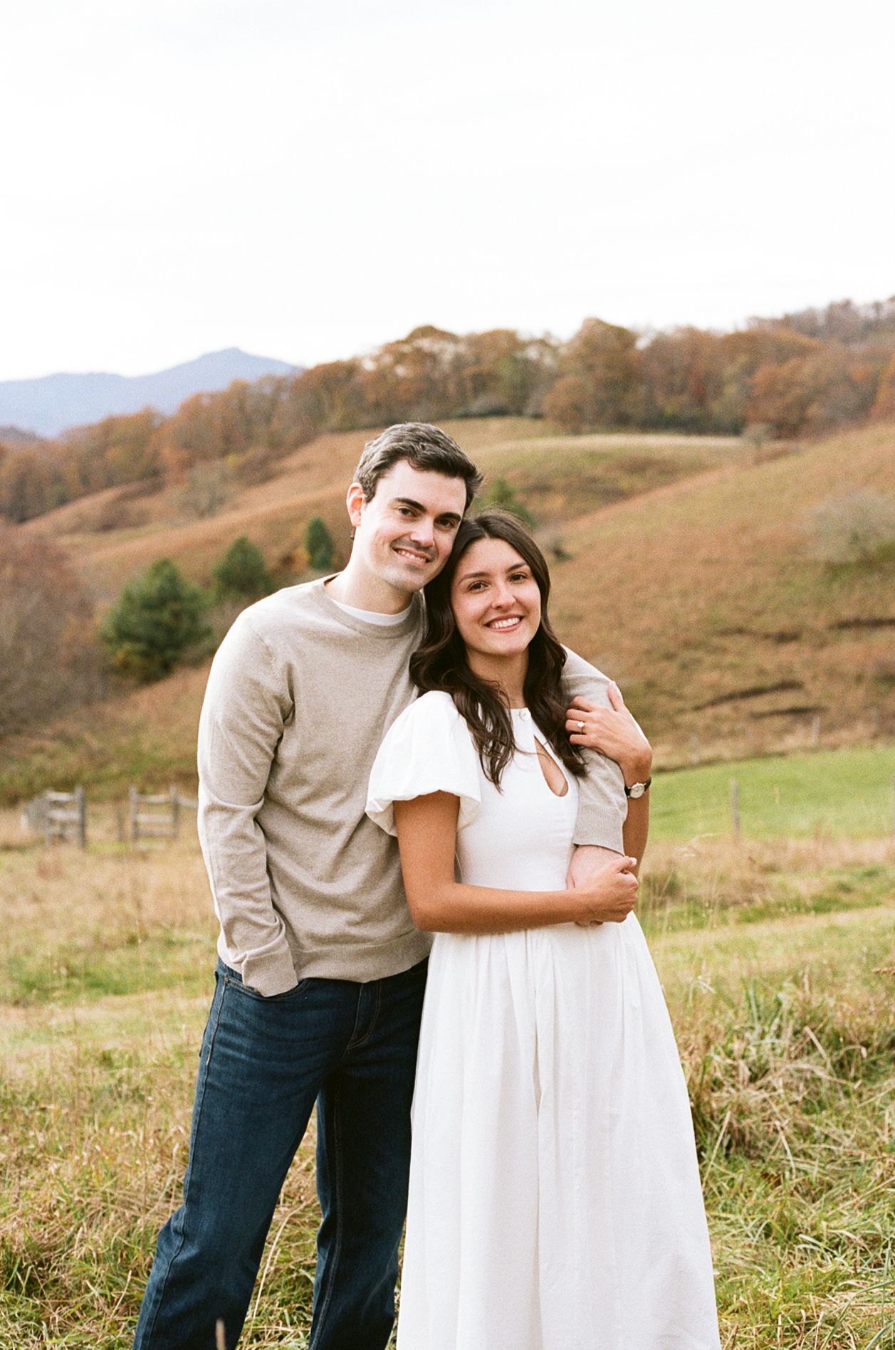 A couple shares a tender moment together in a scenic mountain meadow during golden hour.