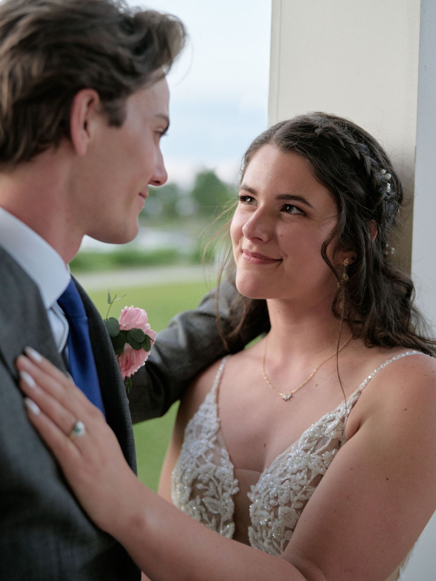 A romantic moment between newlyweds in wedding attire, sharing a tender glance at their outdoor celebration.