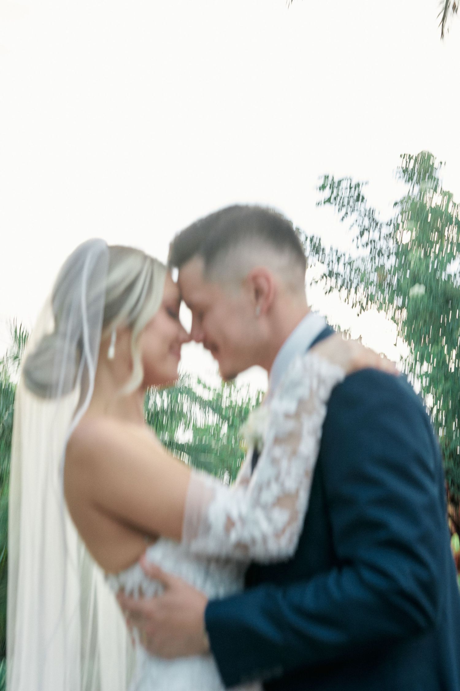 Romantic wedding couple sharing an intimate moment in a garden setting with soft lighting.