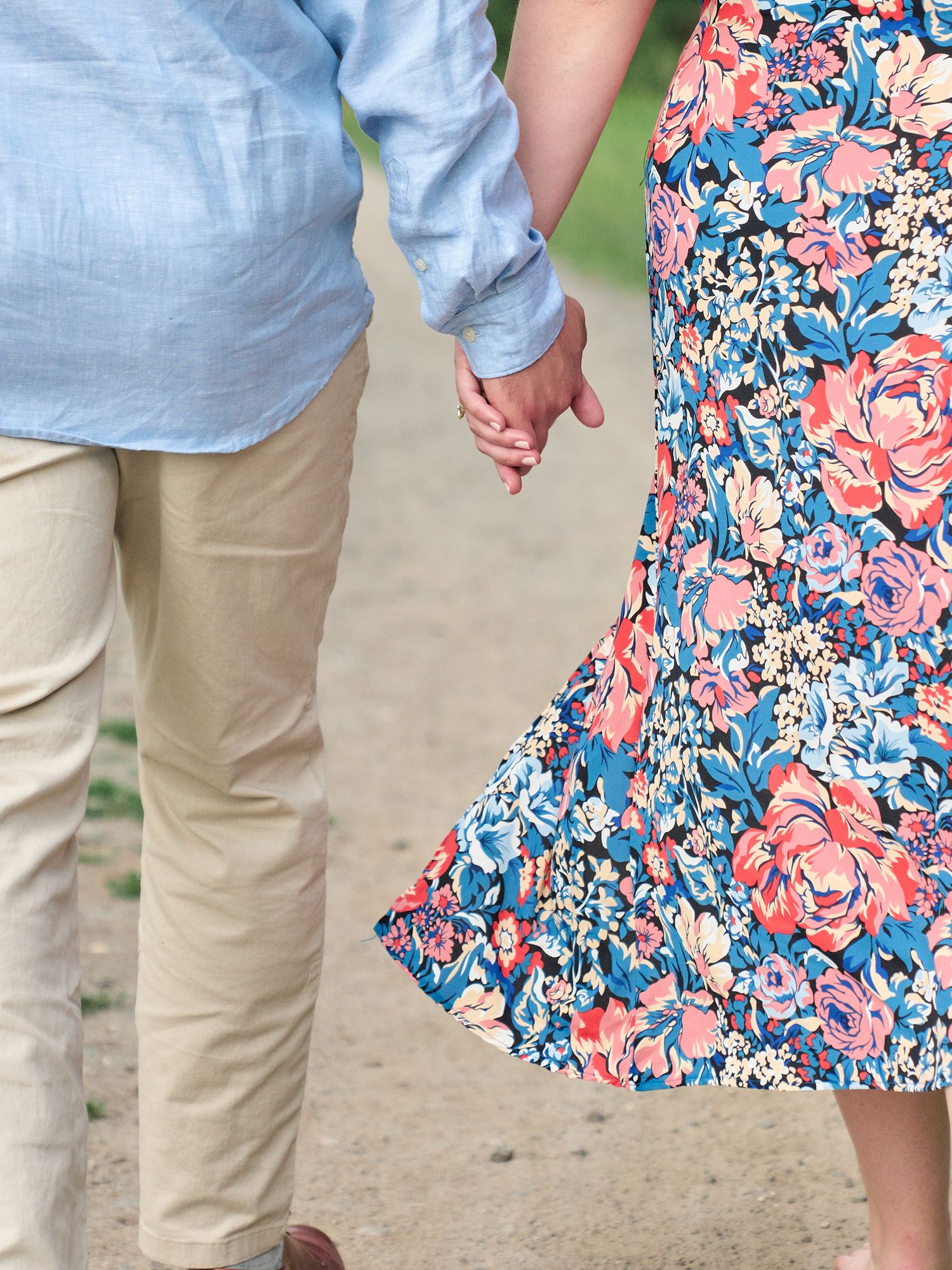 Close-up of clasped hands with floral dress and khaki pants visible.