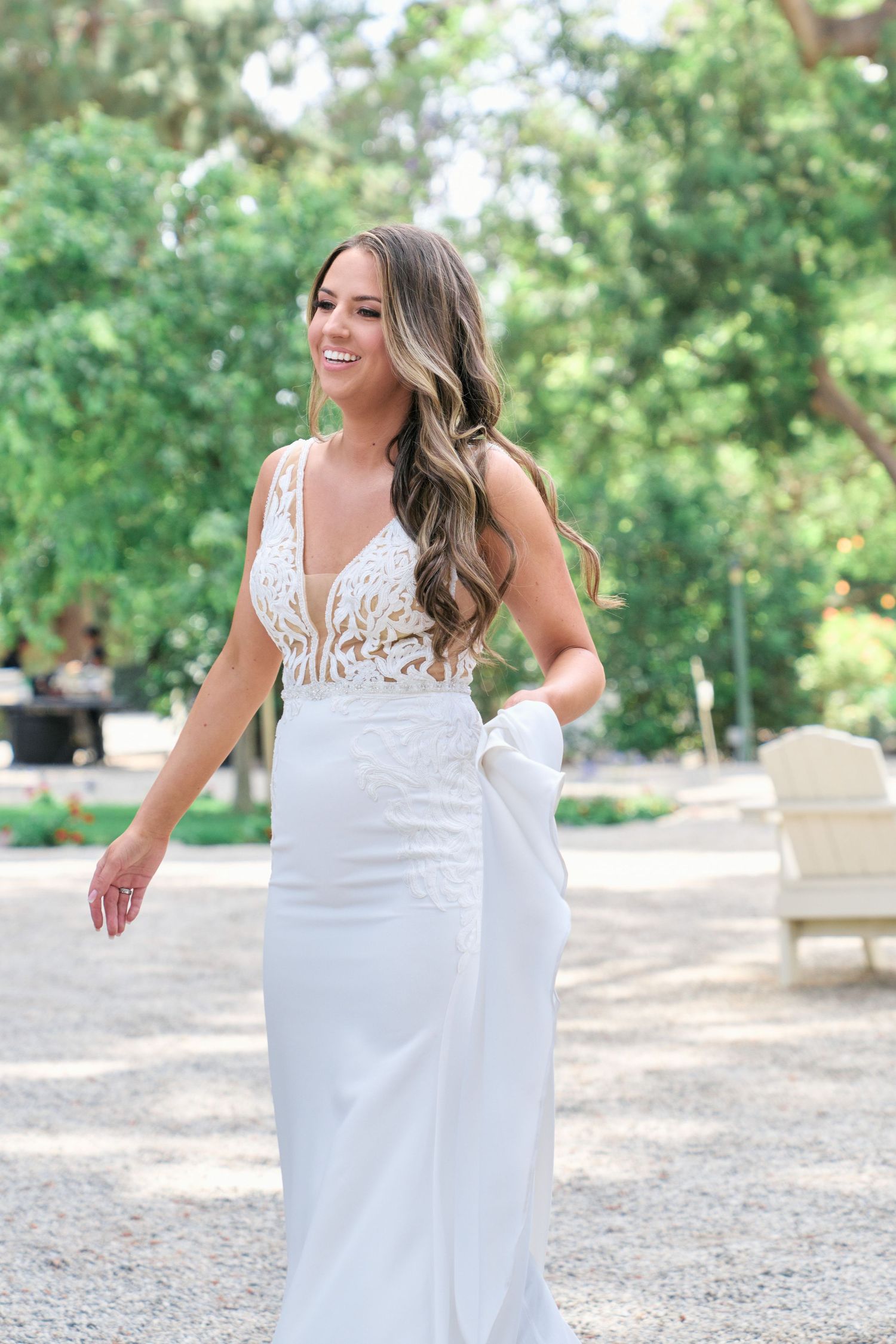 Elegant bride poses in a fitted white lace wedding gown with flowing hair.