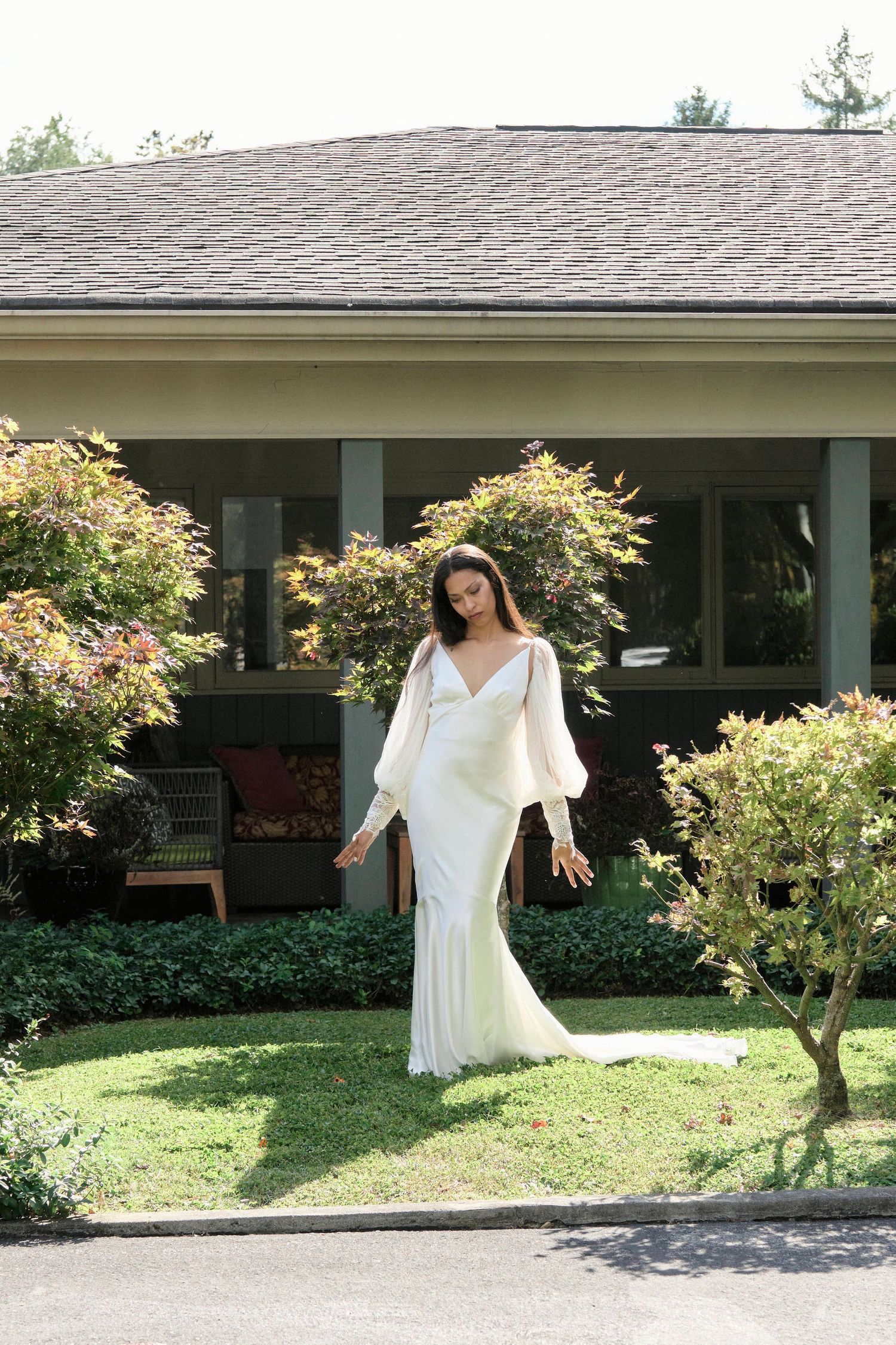bride smelling and posing in the middle of their wedding portrait photos in front of a green bush.