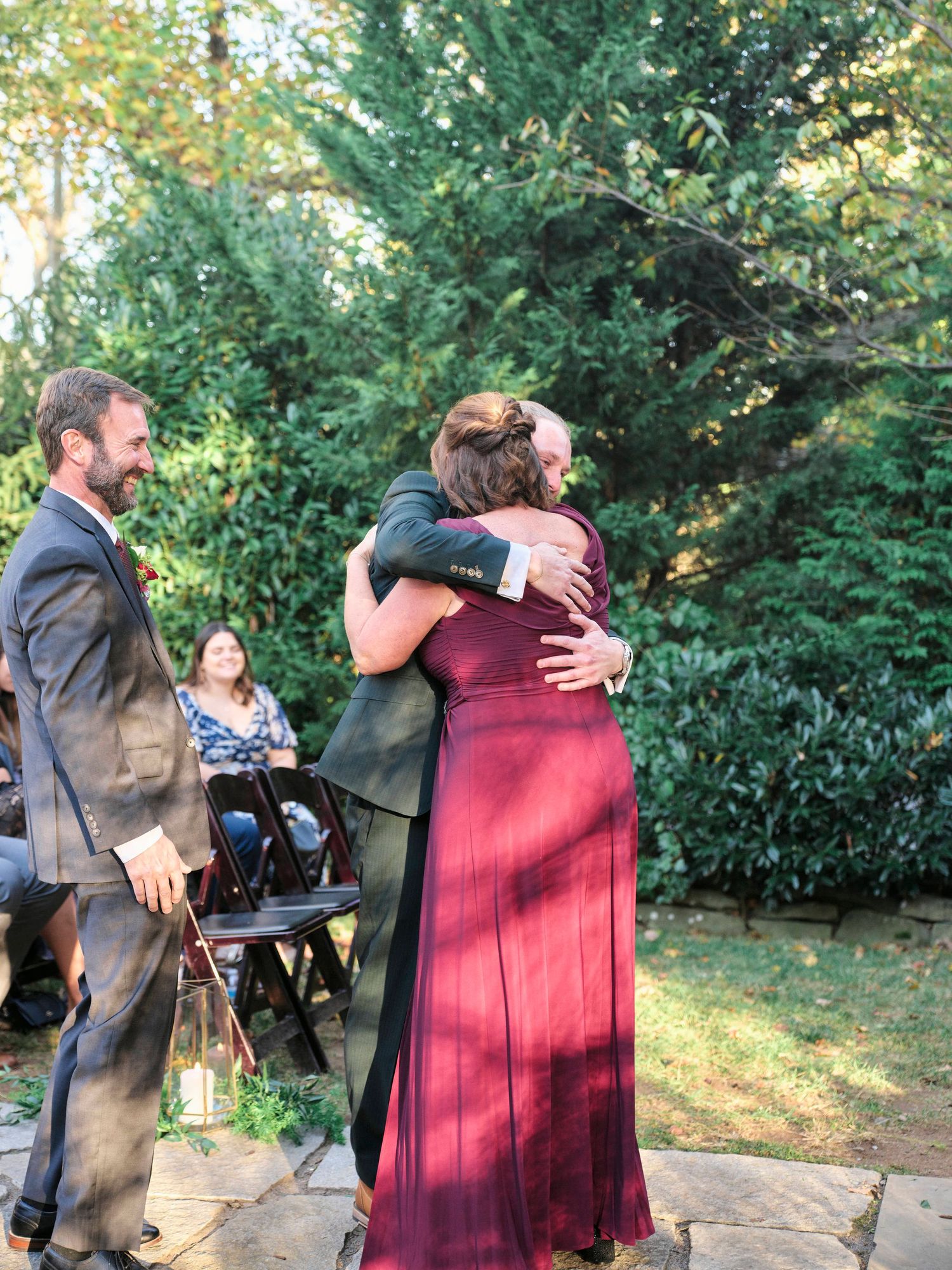 Emotional embrace during outdoor wedding ceremony with guests watching.