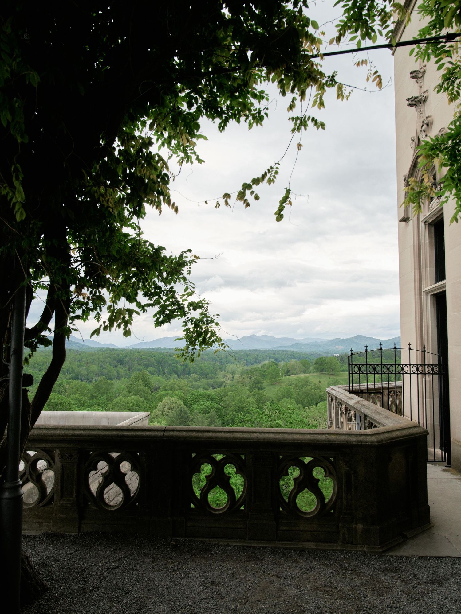 Four scenic views from a stone terrace overlooking a lush green valley with mountains in the distance on a cloudy day.