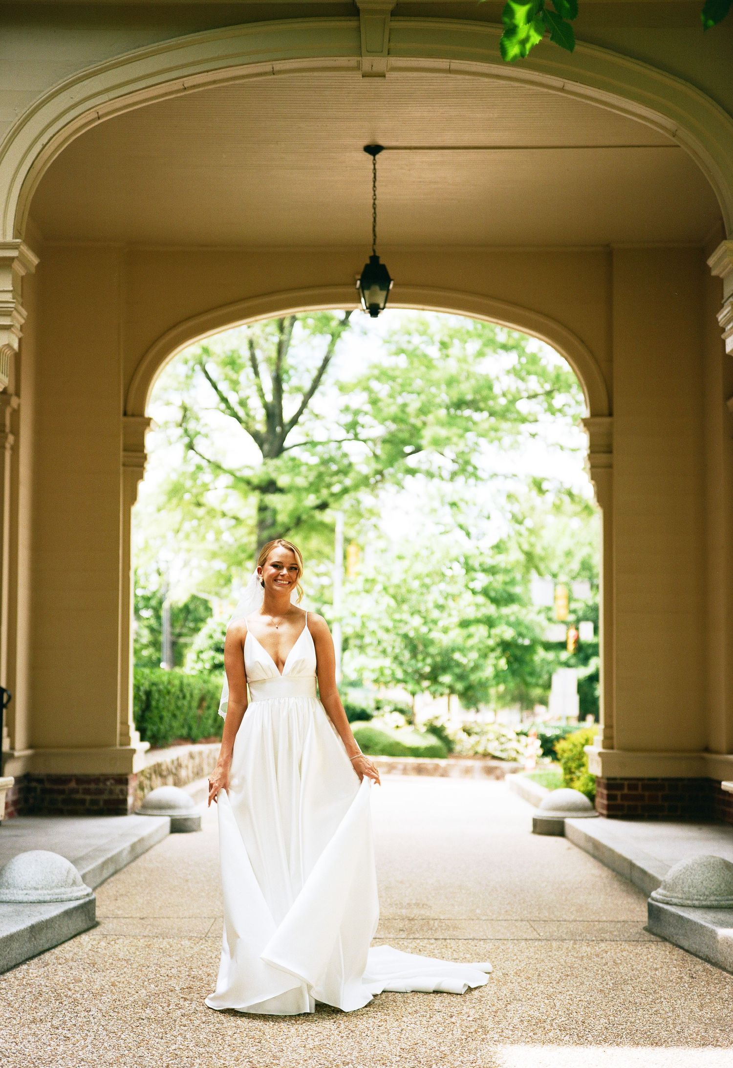 Stunning wedding dress photo under classical architecture with natural garden setting.