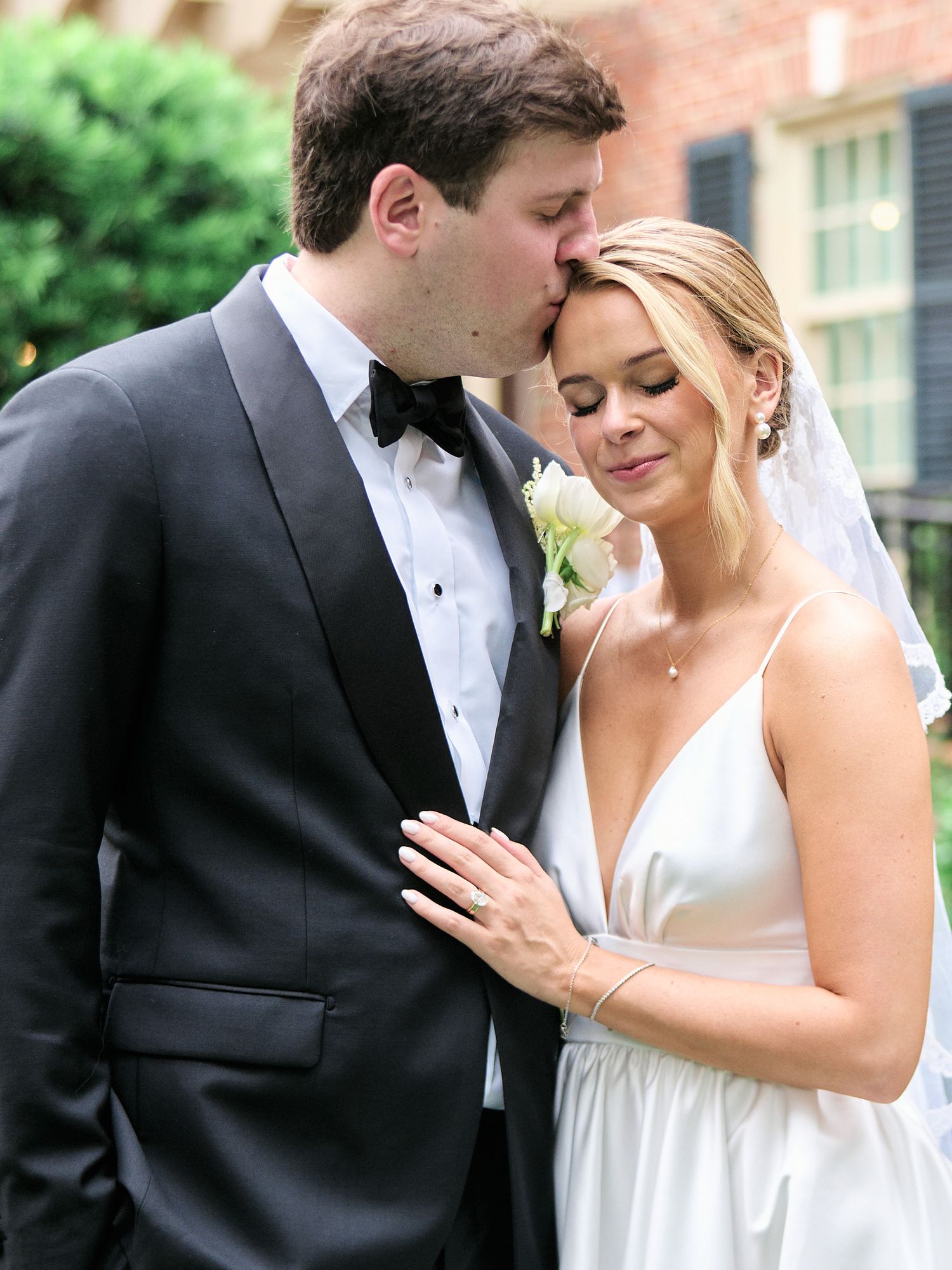 Intimate wedding portrait captured against the backdrop of a historic brick building.