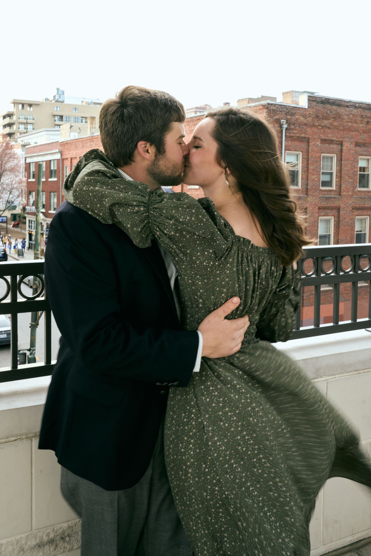 A romantic moment captured between two people in formal wear against an urban backdrop.