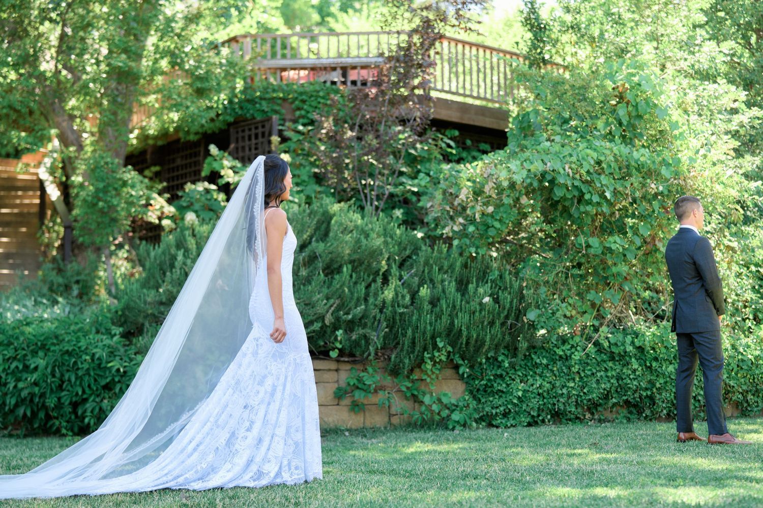A wedding photoshoot in a lush garden setting with decorative wooden structures.